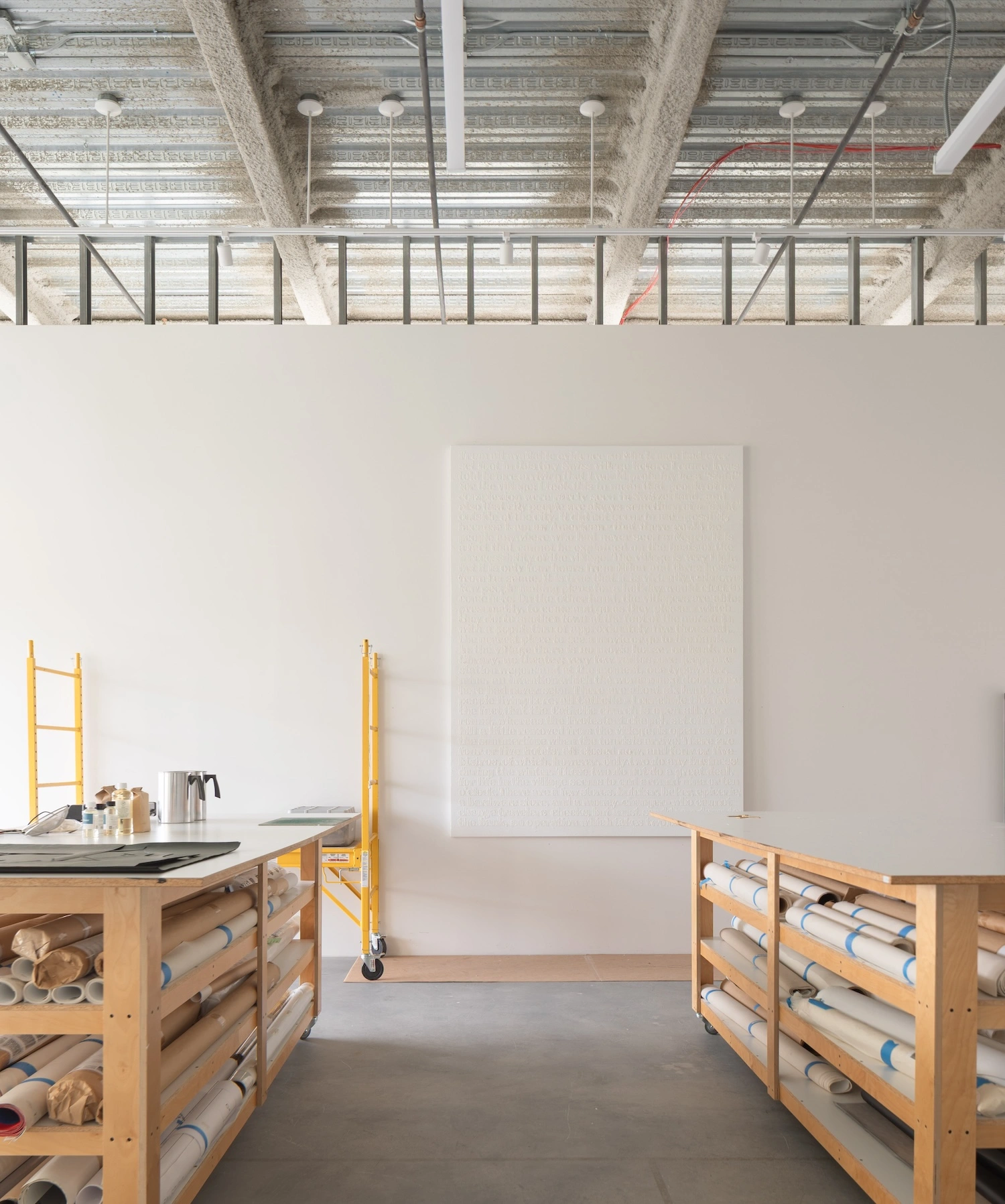 Glenn Ligon Artist’s Studio by Ravi Raj Architect — The studio workspace centers on two timber storage units with visible rolls of canvas and materials organized in horizontal wooden slats.