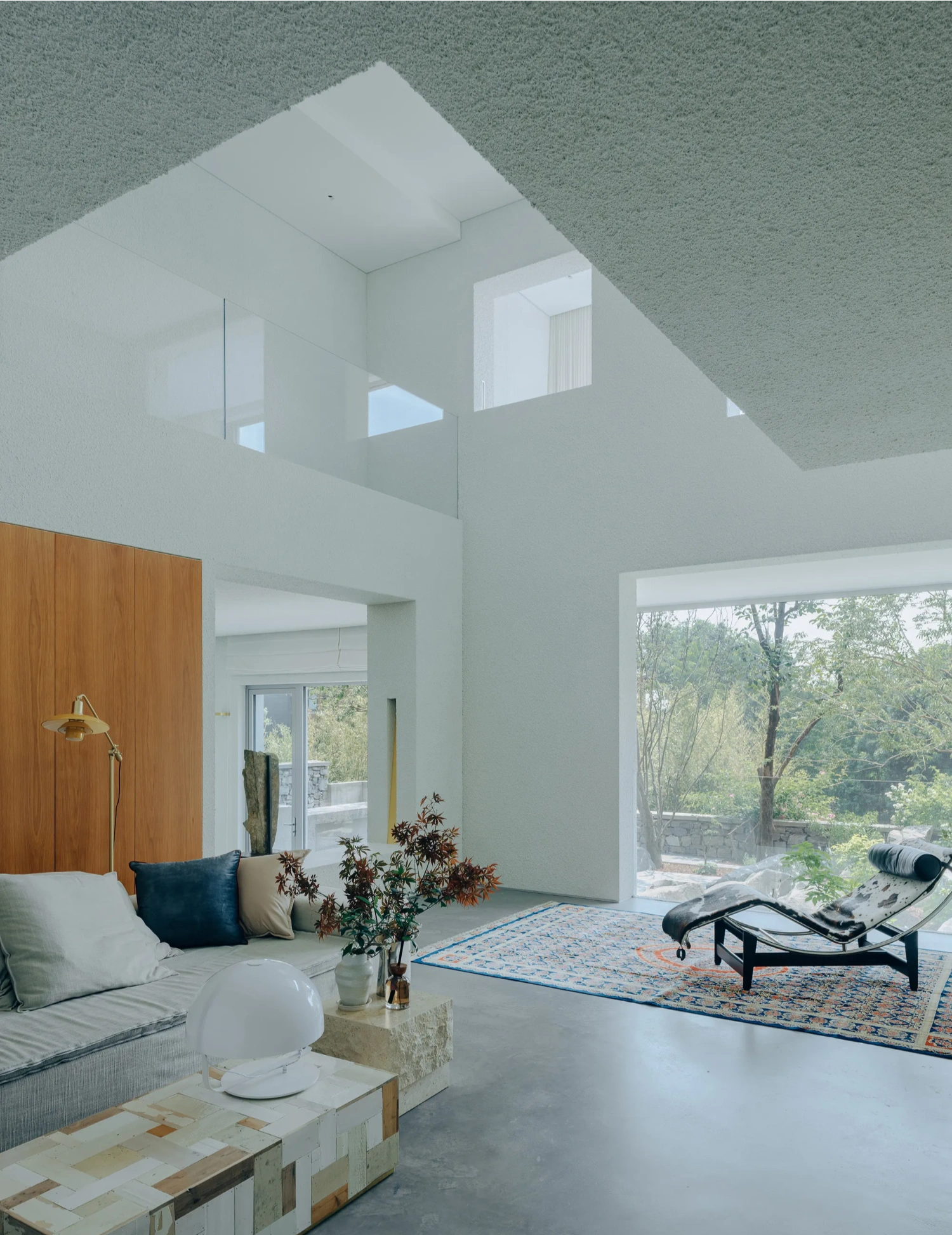 House J in Beijing by Atelier About Architecture — A double-height living space anchored by a rendered plaster volume that frames skylights above.