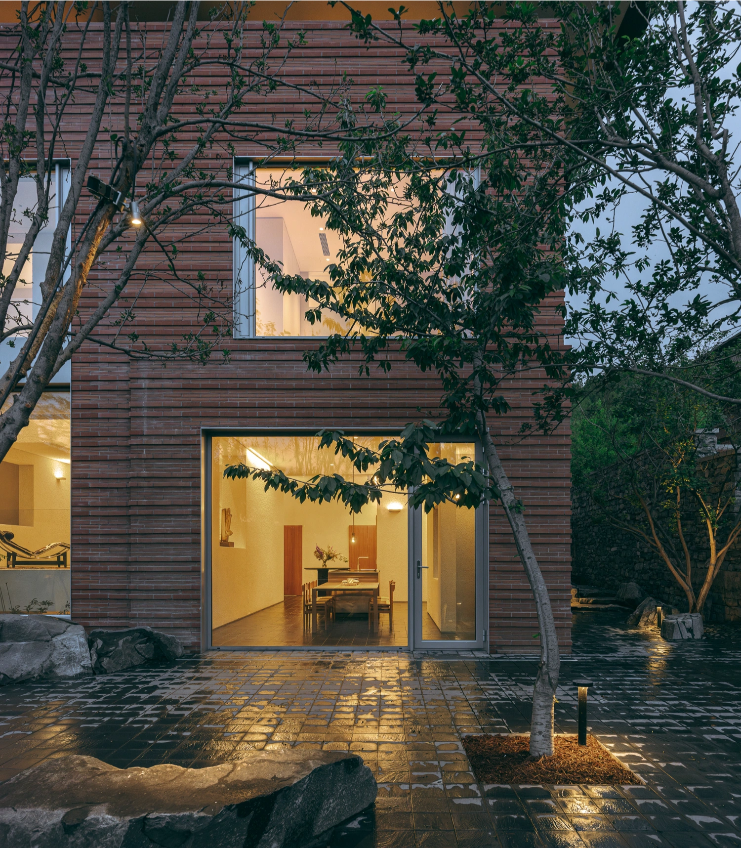 House J in Beijing by Atelier About Architecture — The entrance facade of House J frames a layered interior through a large glazed threshold.