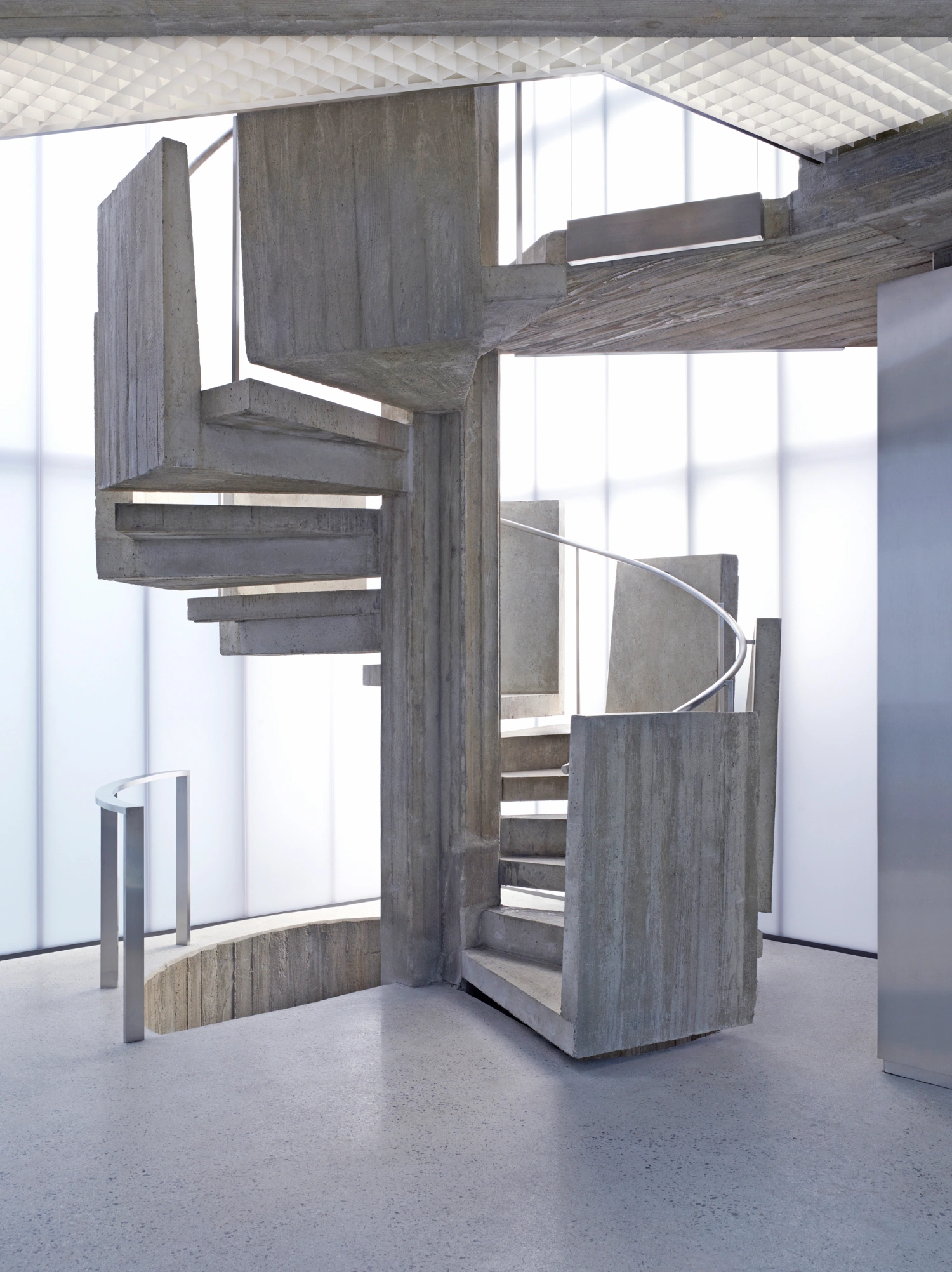 Acne Studios Cheongdam by Sophie Hicks Architects — A sculptural spiral staircase constructed from board-formed concrete dominates this interior view, its monolithic structure ascending through a...