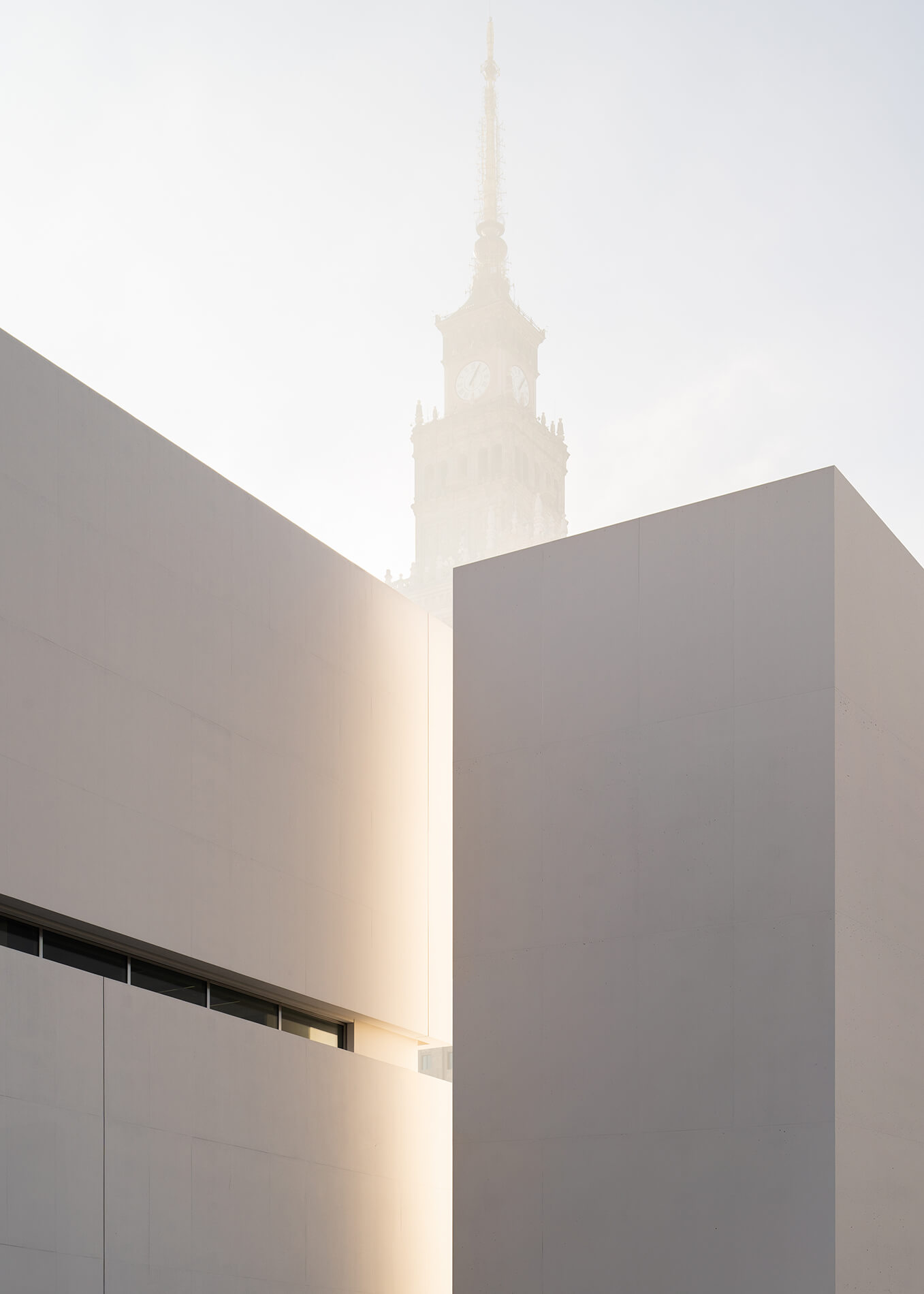 Museum of Modern Art in Warsaw by Thomas Phifer — The Museum of Modern Art's monolithic concrete volume frames a view of Warsaw's Palace of Culture and Science, its spire dissolving into haze beyond.