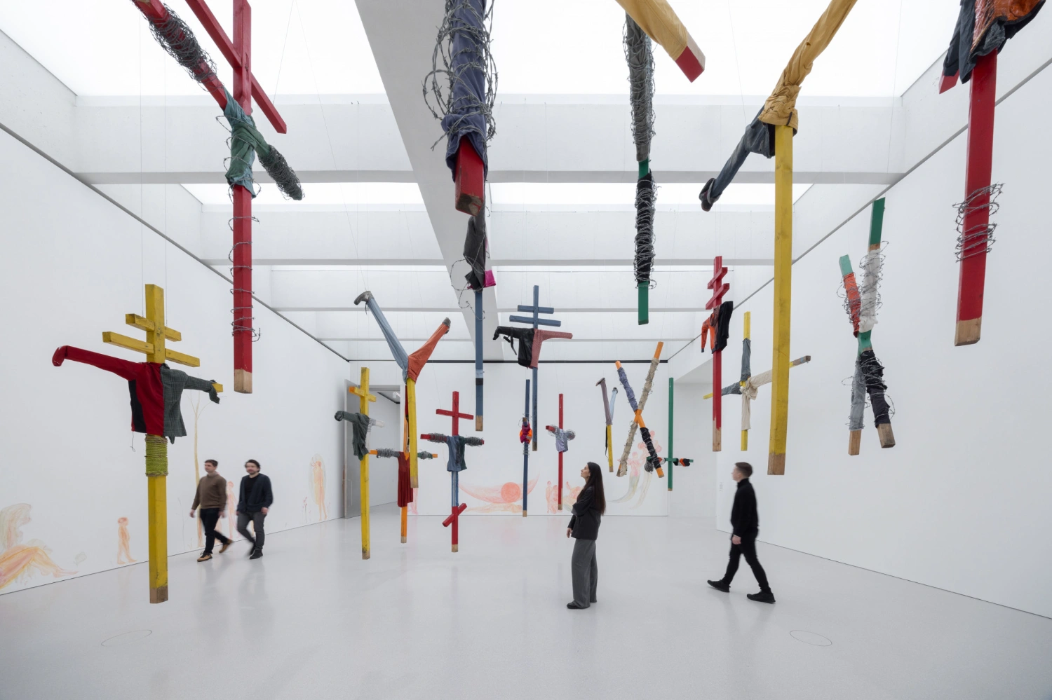Museum of Modern Art in Warsaw by Thomas Phifer — A suspended installation of wooden crosses and fabric-wrapped elements hangs from the skylit ceiling of the Museum of Modern Art's white concrete interior.