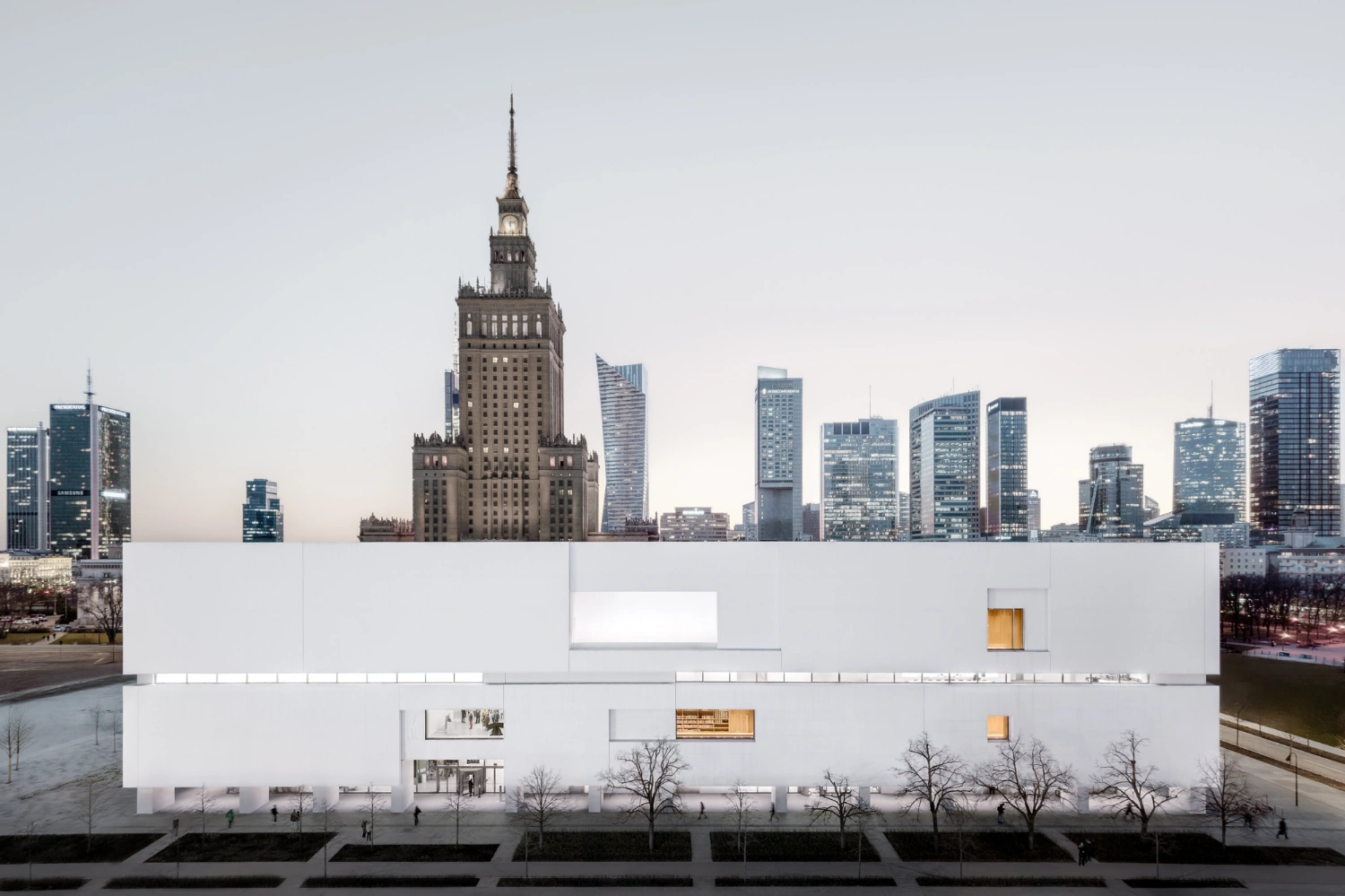 Museum of Modern Art in Warsaw by Thomas Phifer — The Museum of Modern Art's white concrete facade occupies the foreground, its horizontal banding articulated by recessed edges that cast shadow lines across...