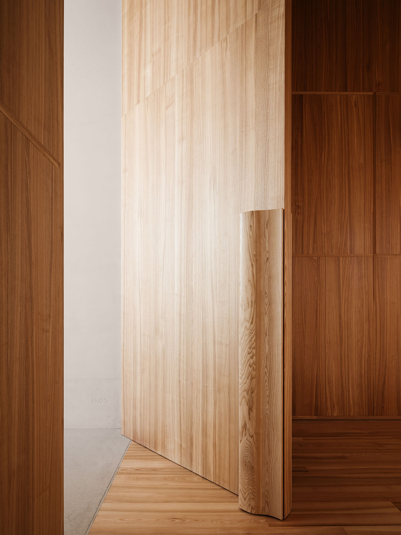 Museum of Modern Art in Warsaw by Thomas Phifer — A light-filled corridor frames the museum's material stratification—darker walnut paneling on the left wall contrasts with pale ash or oak veneer on the...