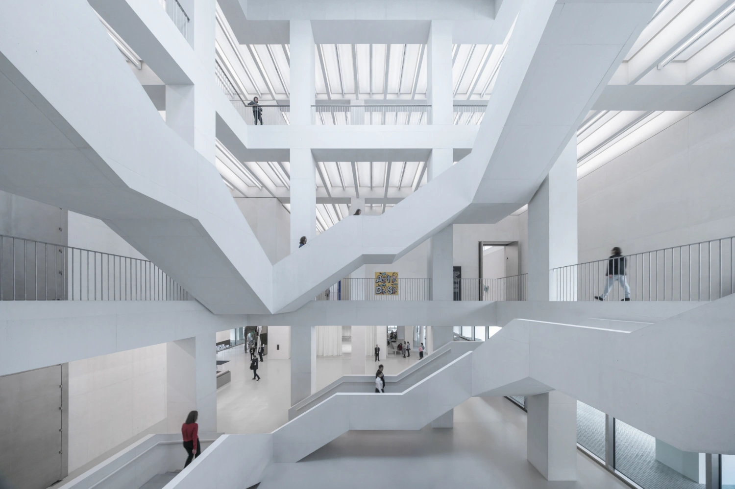 Museum of Modern Art in Warsaw by Thomas Phifer — A multi-story atrium reveals the museum's structural logic through stacked concrete floor plates with recessed edges that cast sharp shadow lines across the...