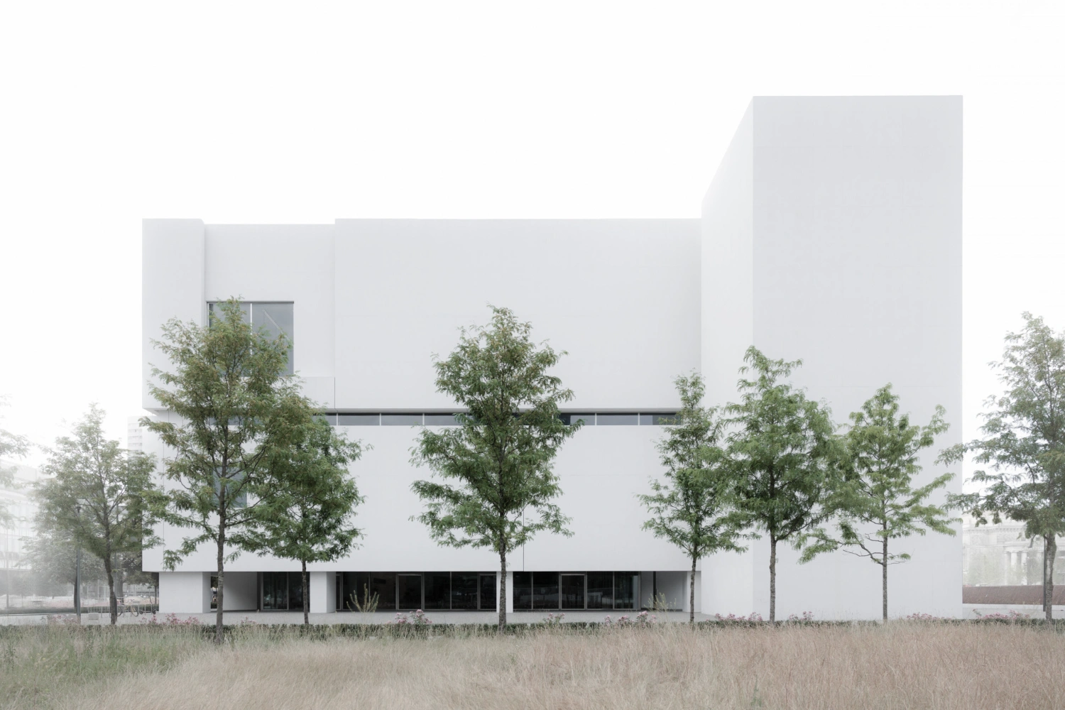 Museum of Modern Art in Warsaw by Thomas Phifer — The Museum of Modern Art's south-facing facade presents a monolithic white concrete form punctuated by mature trees planted at ground level.