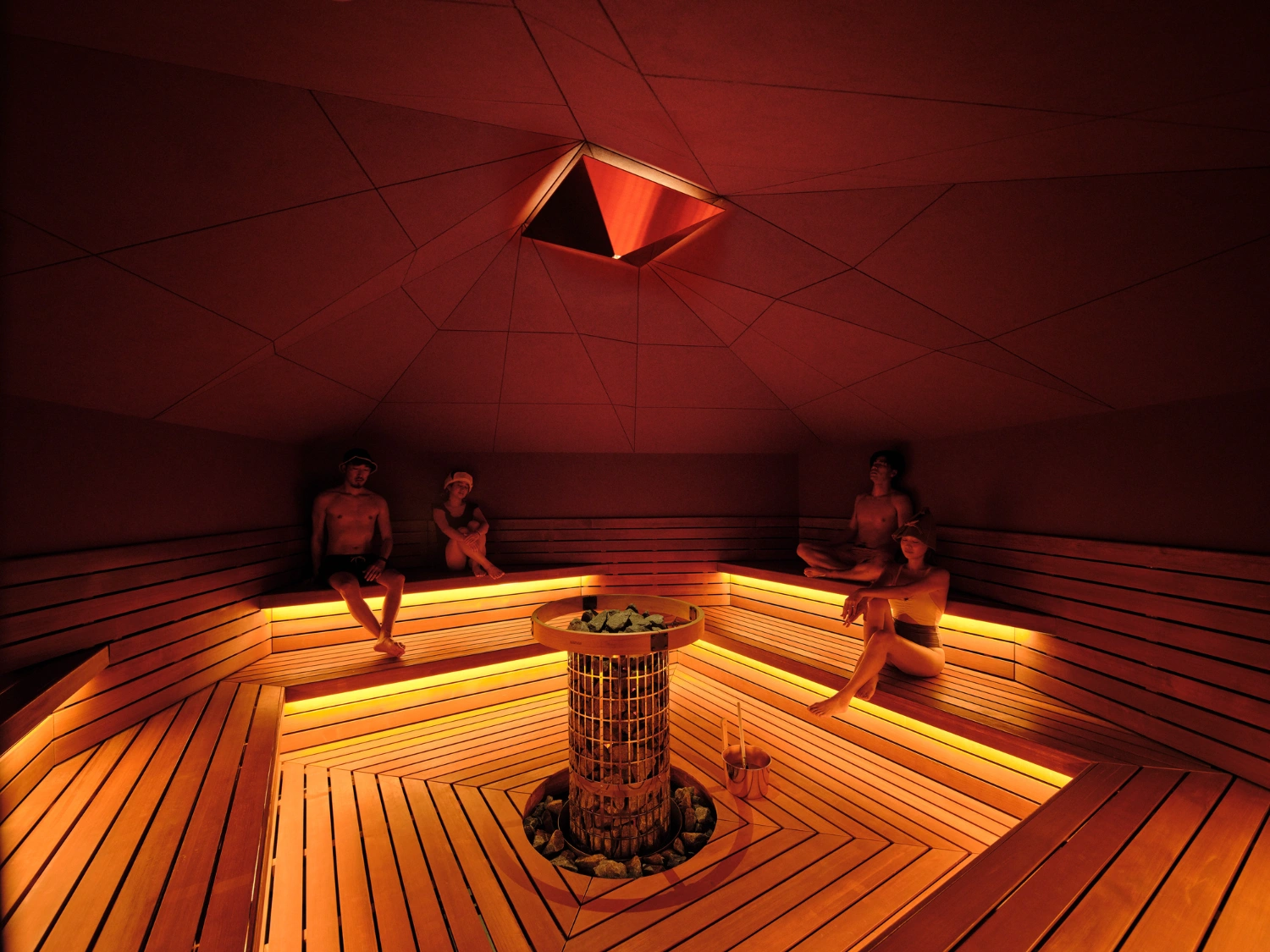 CYCL by YŪ Momoeda Architects — The interior of CYCL sauna reveals a geometric wooden floor with concentric rectangular patterns radiating from a central cylindrical stone-filled heater.