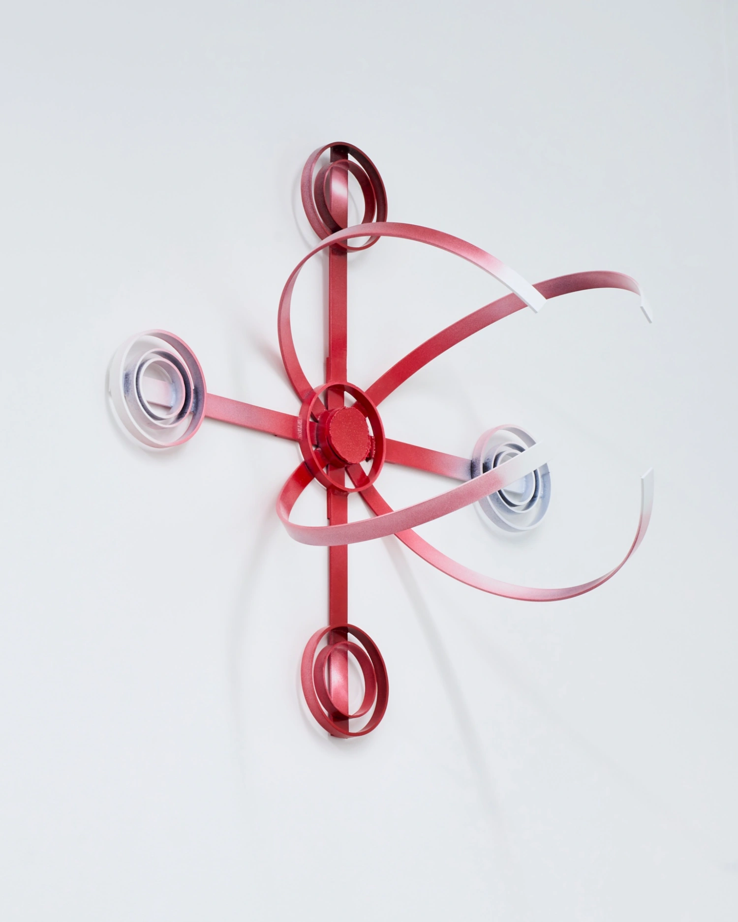 Swarm / Rój by Zuza Golinska at Piktogram — A wall-mounted sculptural installation featuring nested circular wire forms in pink-red metal, creating three-dimensional orbital geometry.