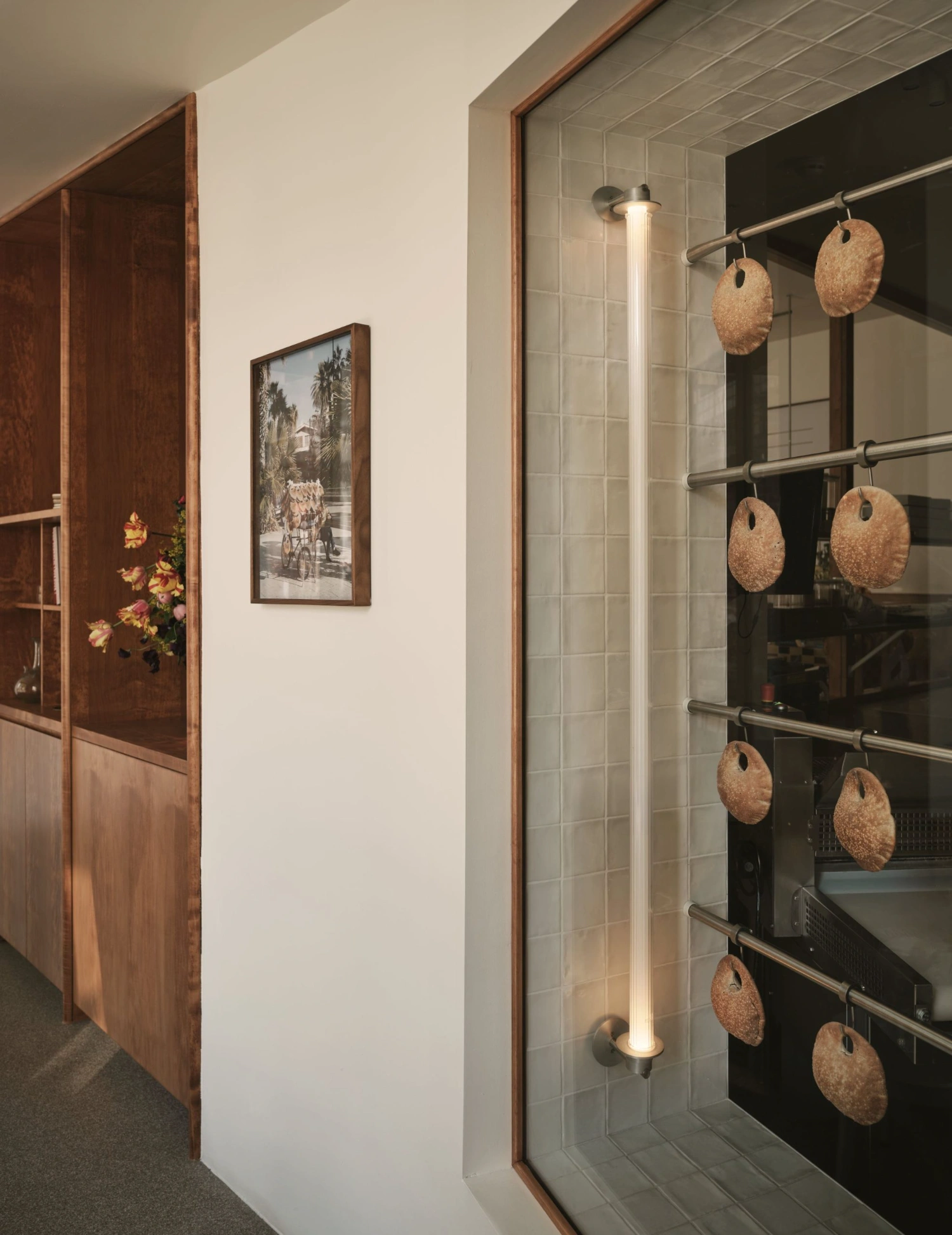 Common Breads bakery by MA Studio — Display window featuring cork-finished circular bread forms suspended from horizontal brass rods at varying heights, creating a rhythmic vertical composition.