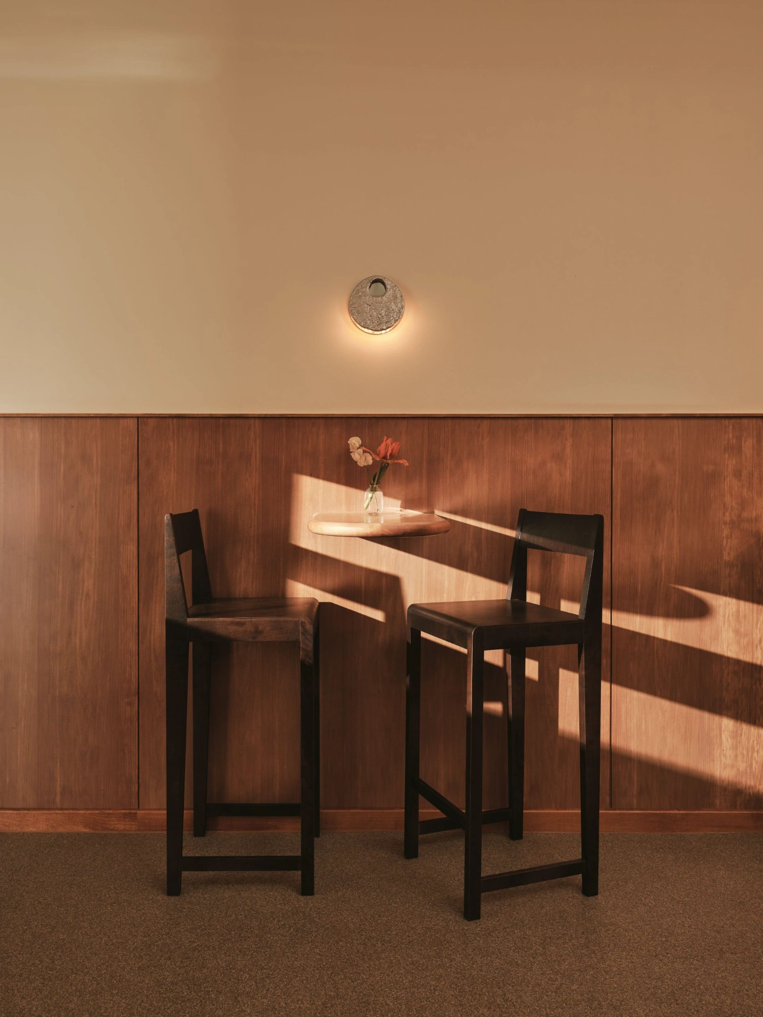 Common Breads bakery by MA Studio — A minimalist seating vignette within the Common Breads bakery reveals the interplay of natural light and material warmth.