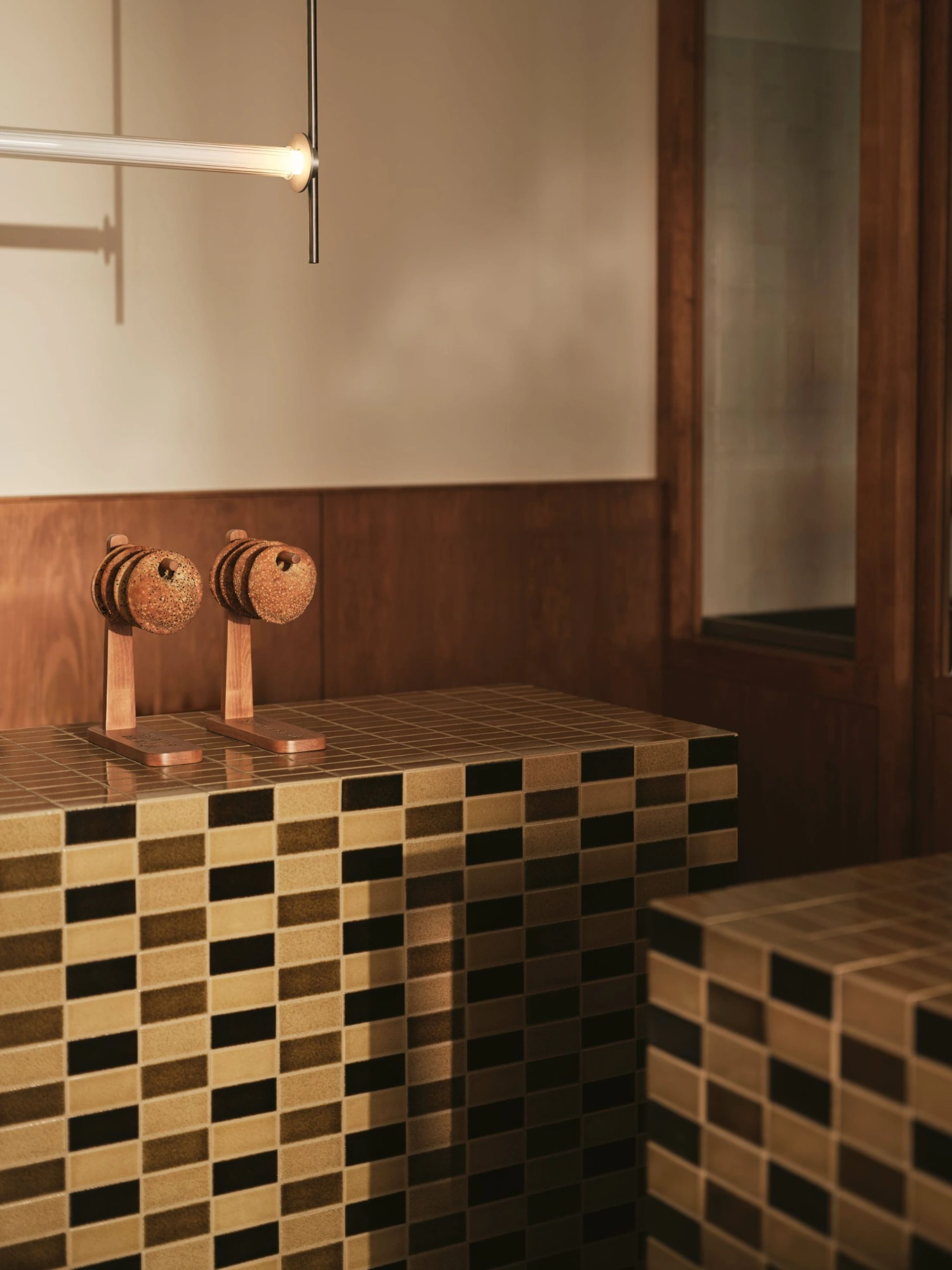 Common Breads bakery by MA Studio — A detail view of Common Breads' interior counter space featuring a distinctive checkered tile pattern in cream, black, and taupe tones.