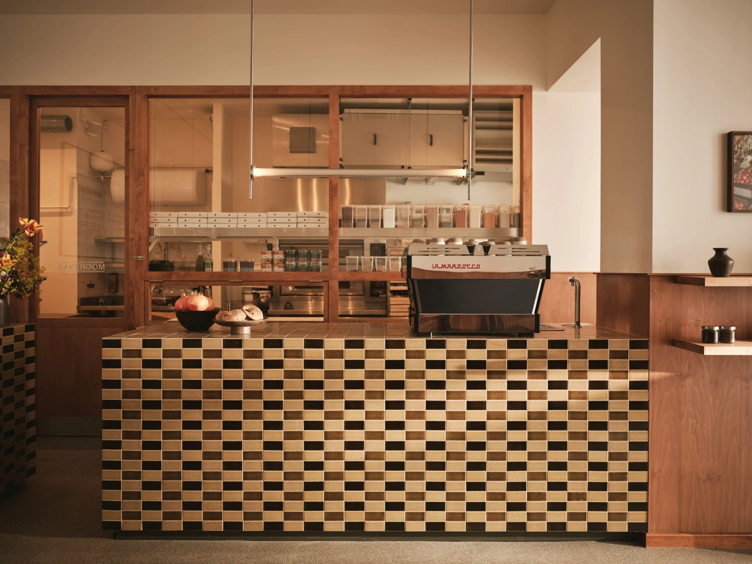 Common Breads bakery by MA Studio — Common Breads' counter showcases a distinctive checkered tile facade in cream, tan, and charcoal—a direct reference to Levantine street-vendor tradition.