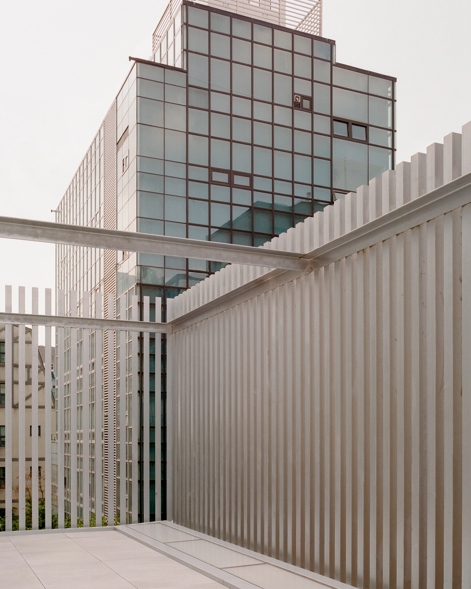 K-Auction Exhibition Hall Sinsa by min_workshop + 3ab — A passage within K-Auction Exhibition Hall reveals the interplay of material finishes: vertical bronze-framed glazing with gridded muntins creates a strong...