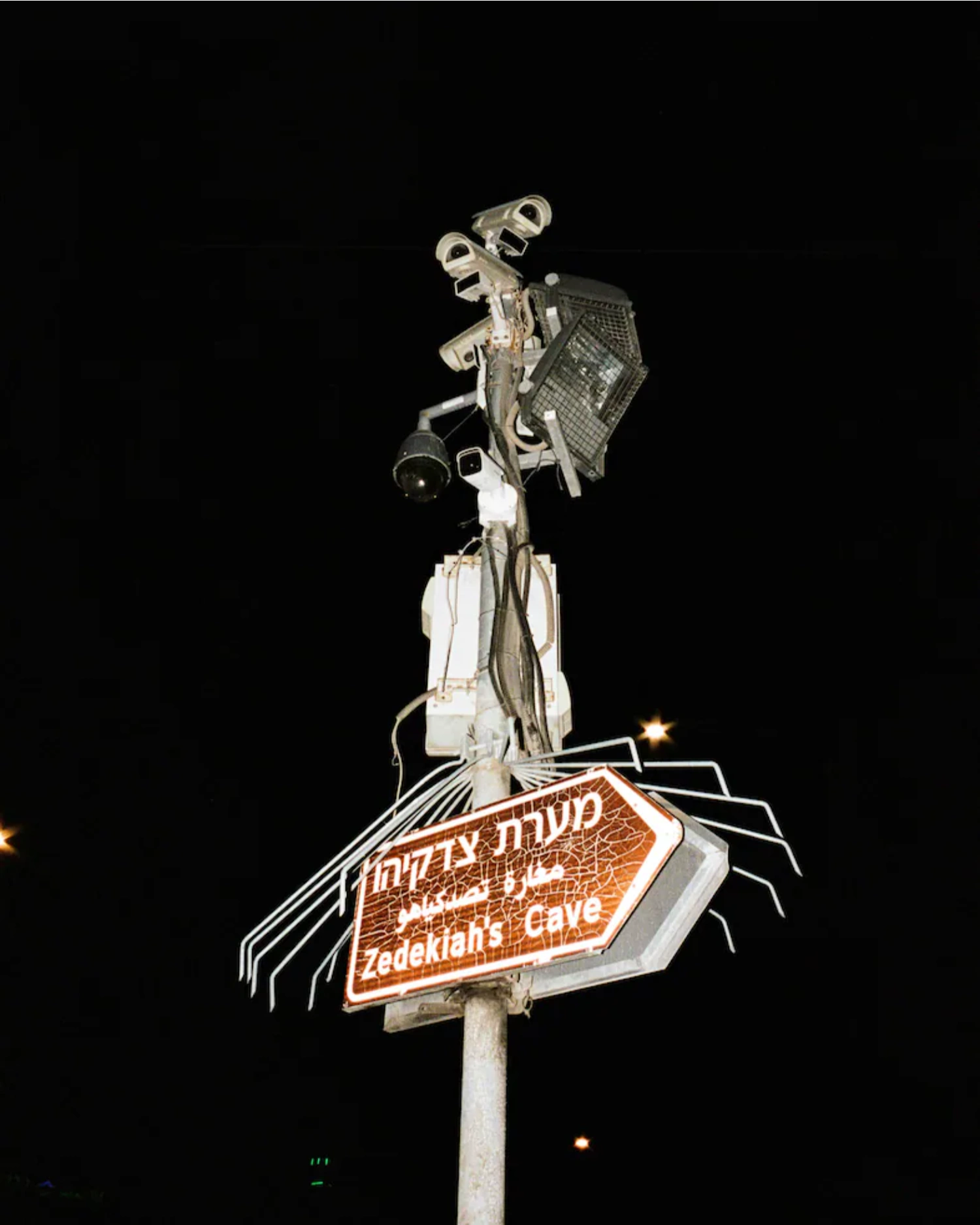 Before Freedom by Adam Rouhana — A nighttime photograph of a vintage neon sign mounted on a tall pole against a black sky.