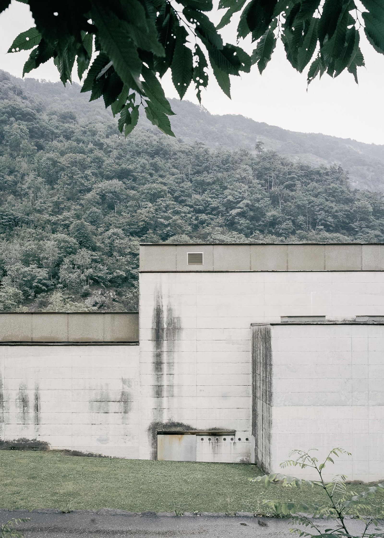 La Congiunta Museum by Peter Märkli — A concrete wall structure reveals the imprint of wooden formwork across its surface, with visible water staining and weathering marks descending vertically.