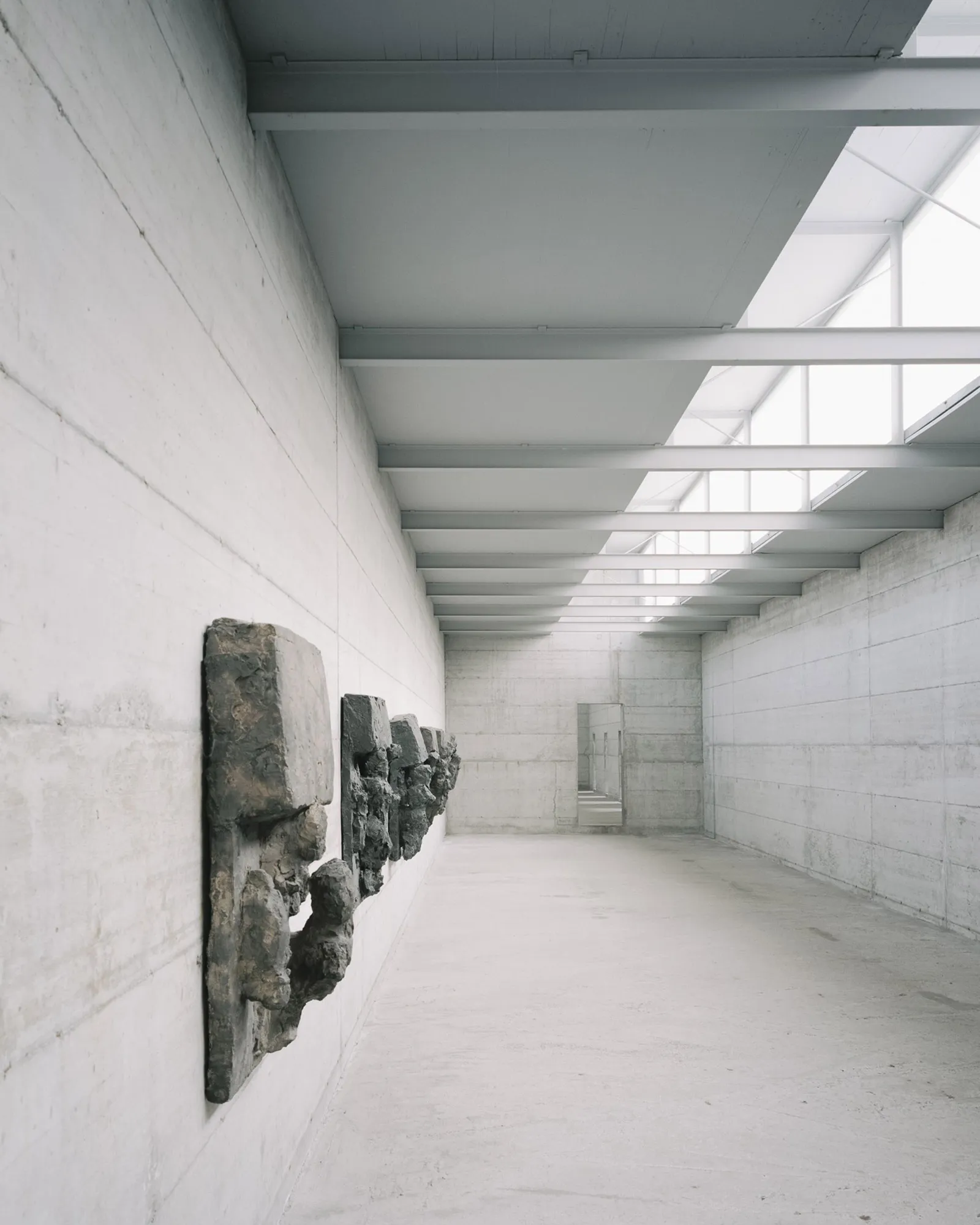 La Congiunta Museum by Peter Märkli — A corridor within La Congiunta Museum extends toward vanishing point, its board-formed concrete walls bearing impressions of wooden formwork.