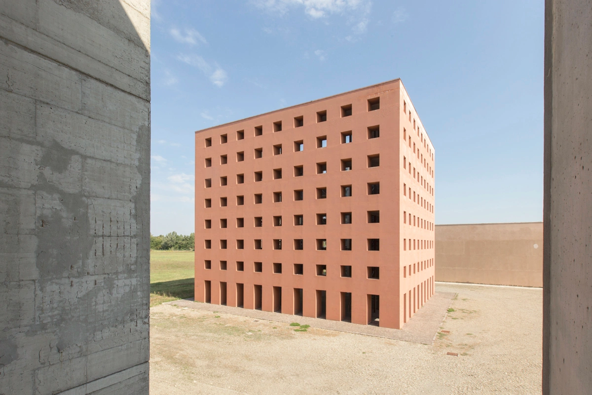 San Cataldo Cemetery by Aldo Rossi — A terracotta brick volume presents a rigid grid of square window voids arranged in systematic rows across its cubic facade.