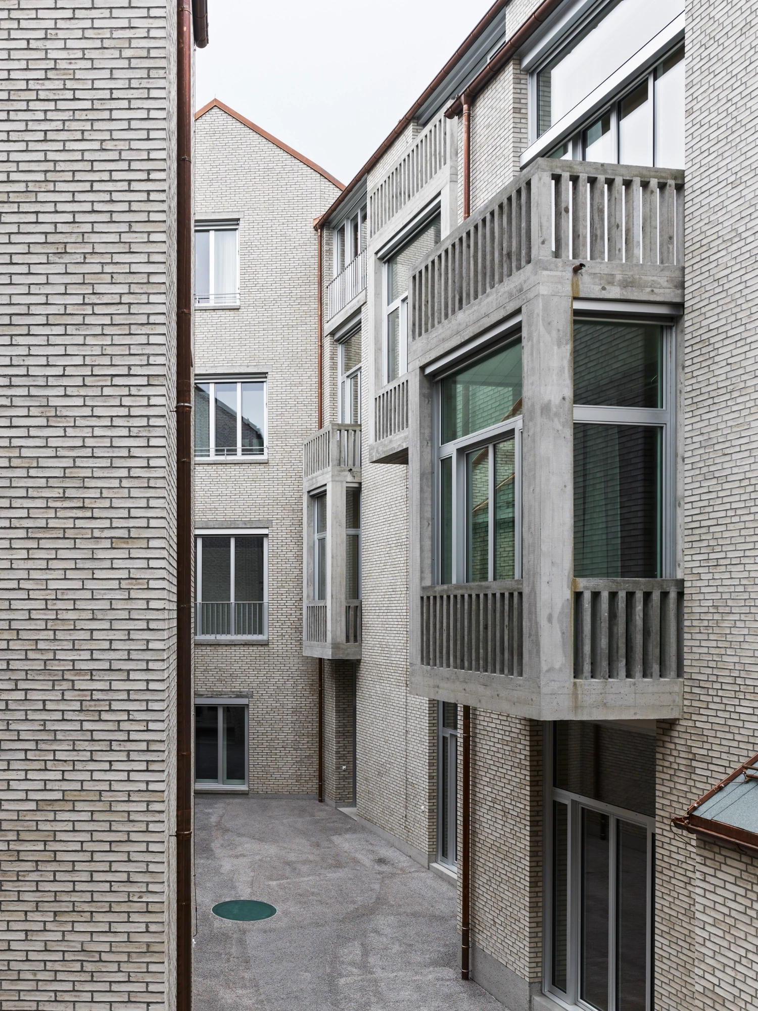 Jazz Campus by Buol & Zünd — A narrow courtyard passage between brick facades reveals the project's exterior spatial strategy.