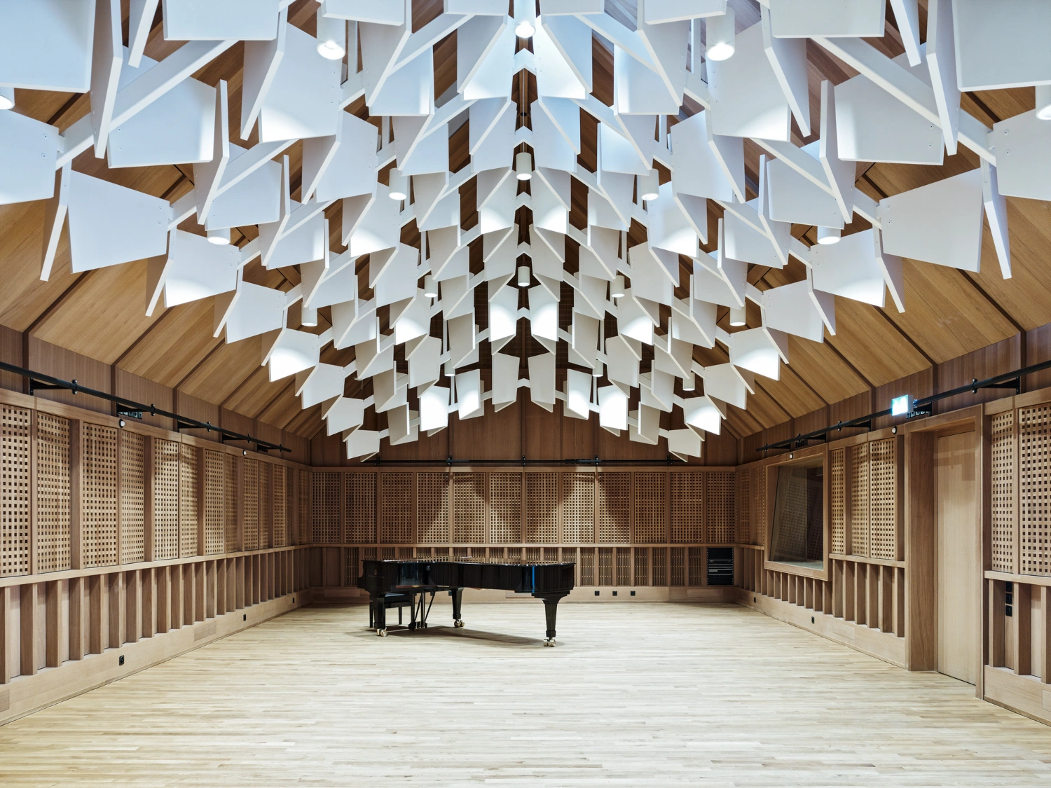 Jazz Campus by Buol & Zünd — A music hall interior centered on a grand piano positioned beneath a suspended three-dimensional ceiling canopy.