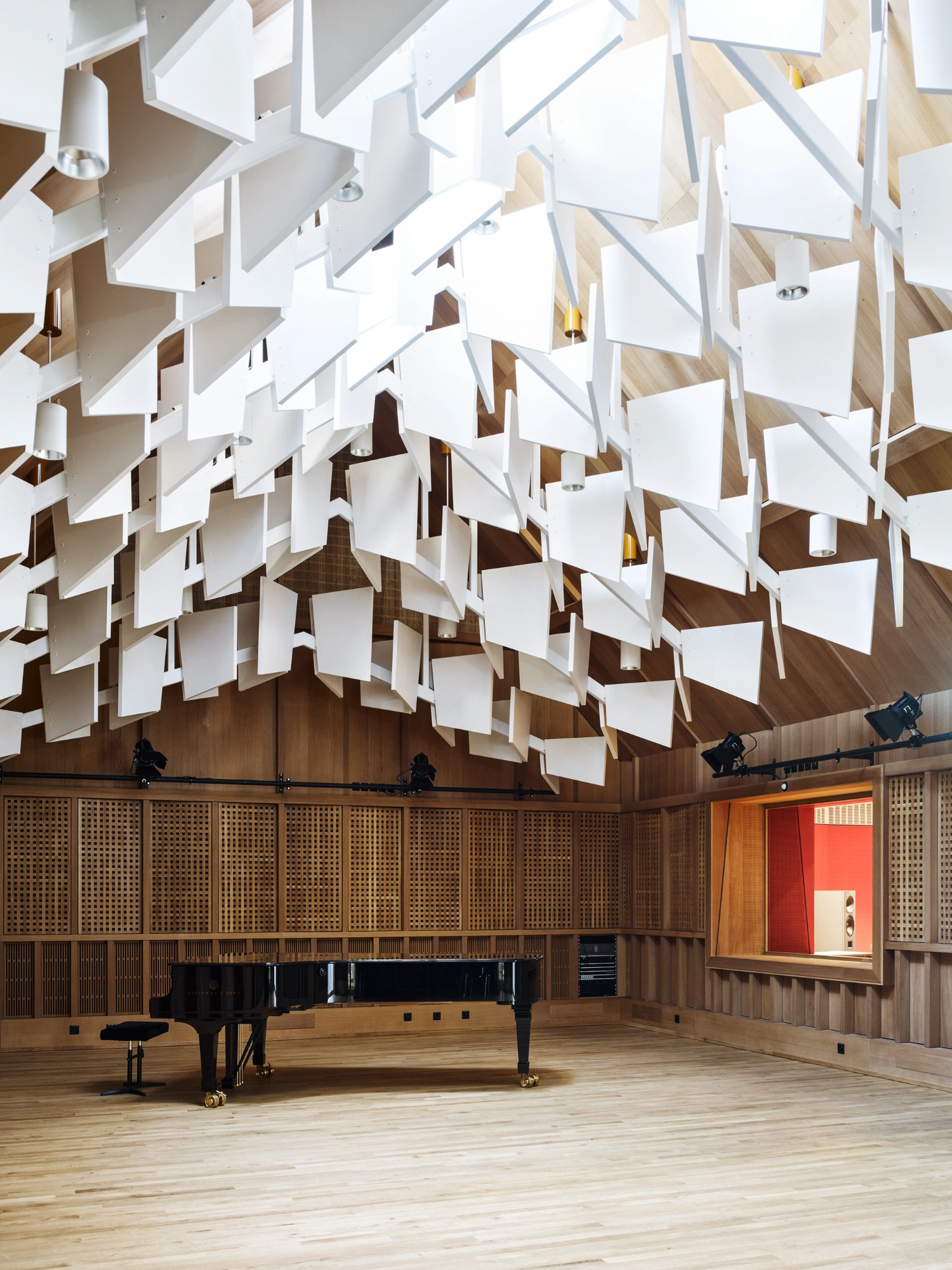 Jazz Campus by Buol & Zünd — A music rehearsal space anchored by a grand piano positioned centrally on light oak flooring.