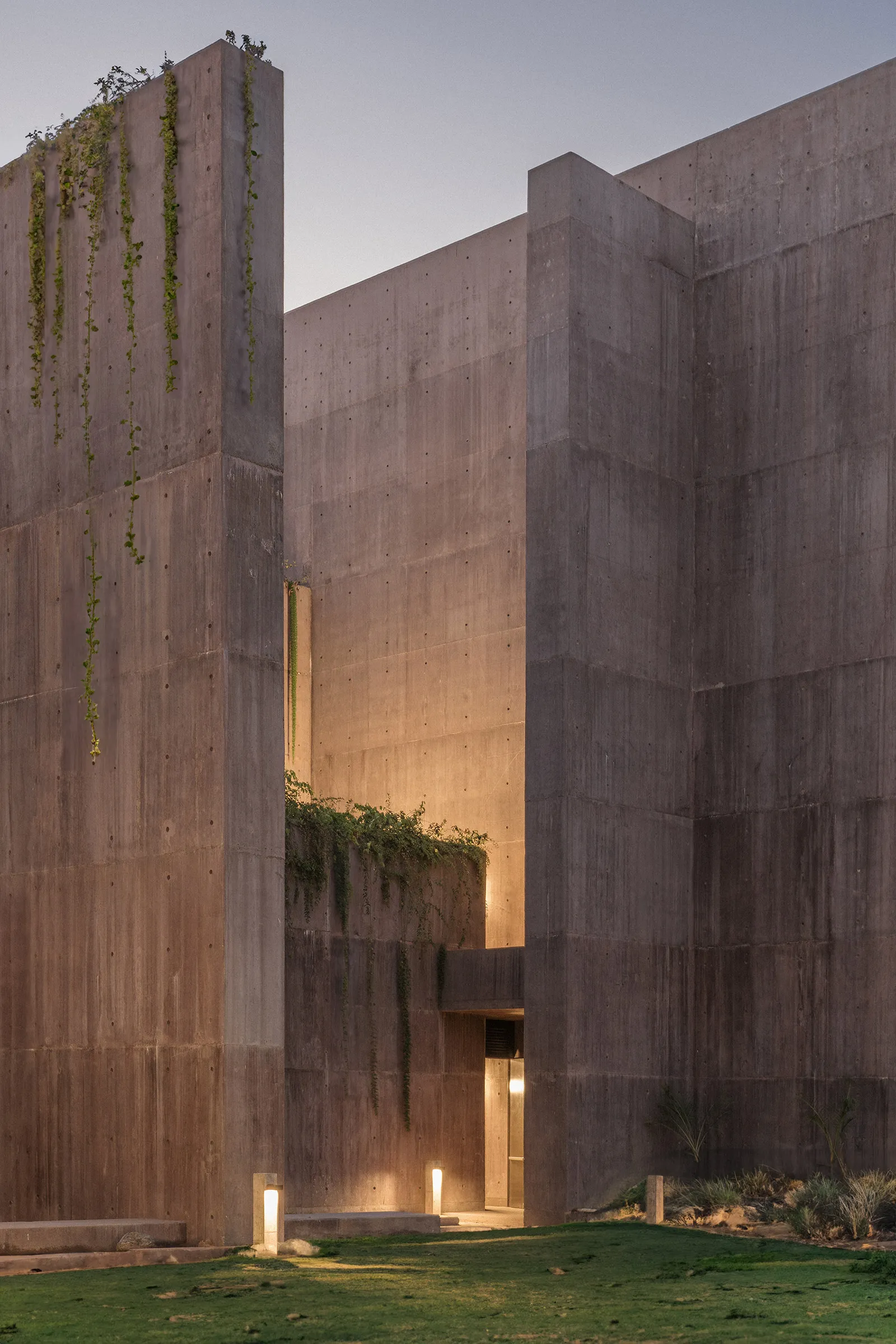 Sea of Cortez Research Center by Tatiana Bilbao — Towering board-formed concrete walls create a monolithic courtyard entrance, their weathered surfaces marked by formwork texture and rust-colored staining.