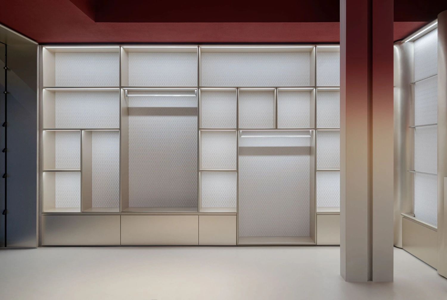 Missoni Home Boutique (Showroom) by Lit Studio — The showroom's modular display system dominates the composition, a rectilinear grid of white-backed shelving units with horizontal aluminum divisions...