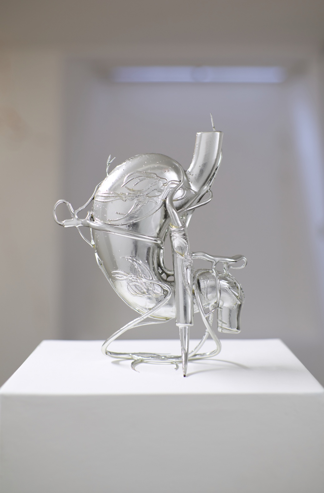 Opacity As A Healing Space by Szilvia Bolla Lorenzo Conforti at Limbo Contemporary — A sculptural glass form dominates the white plinth, its translucent resin body defined by undulating biomorphic curves that suggest fluid movement frozen in...