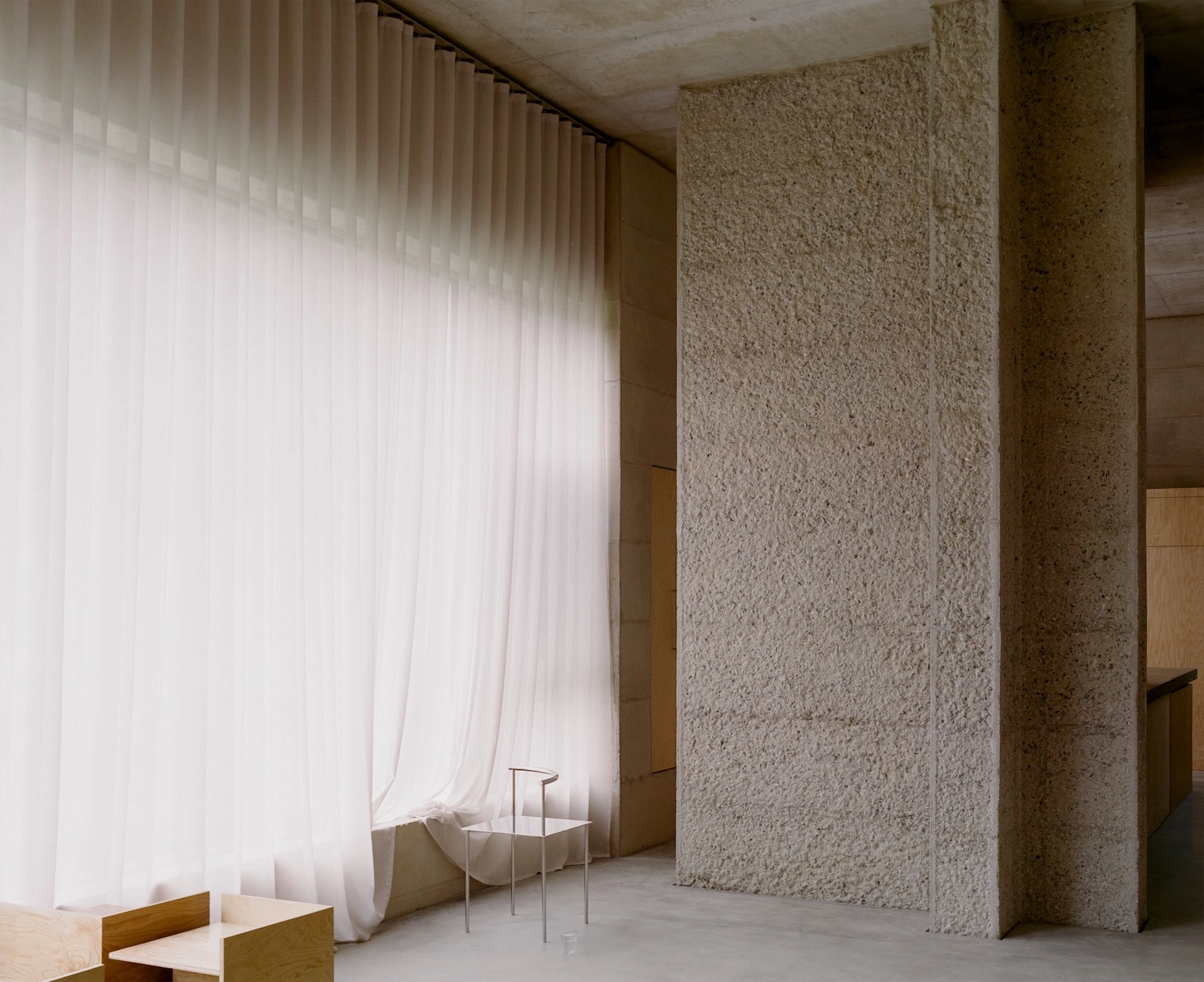 Raw House by Order Matter — A compressed passage frames the Raw House interior through contrasting material zones.