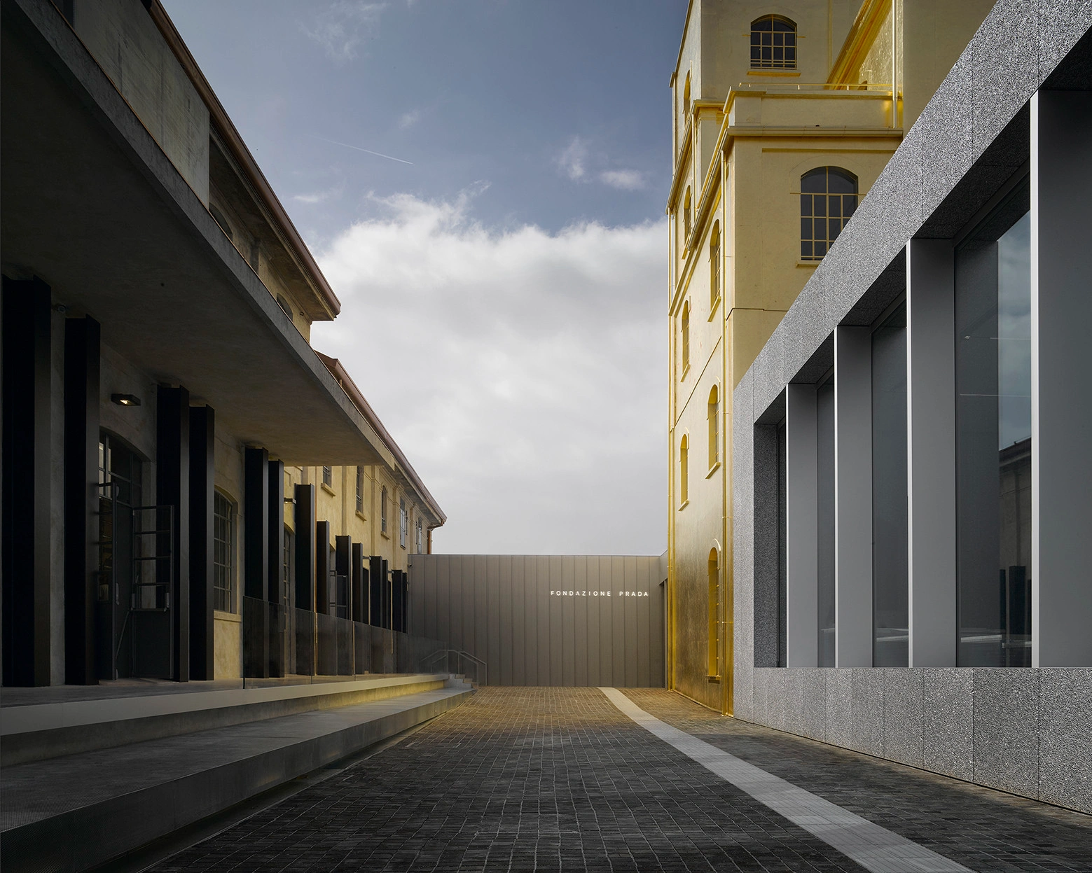 Fondazione Prada by OMA — The courtyard passage between OMA's Prada complex demonstrates deliberate architectural heterogeneity through material and formal contrast.