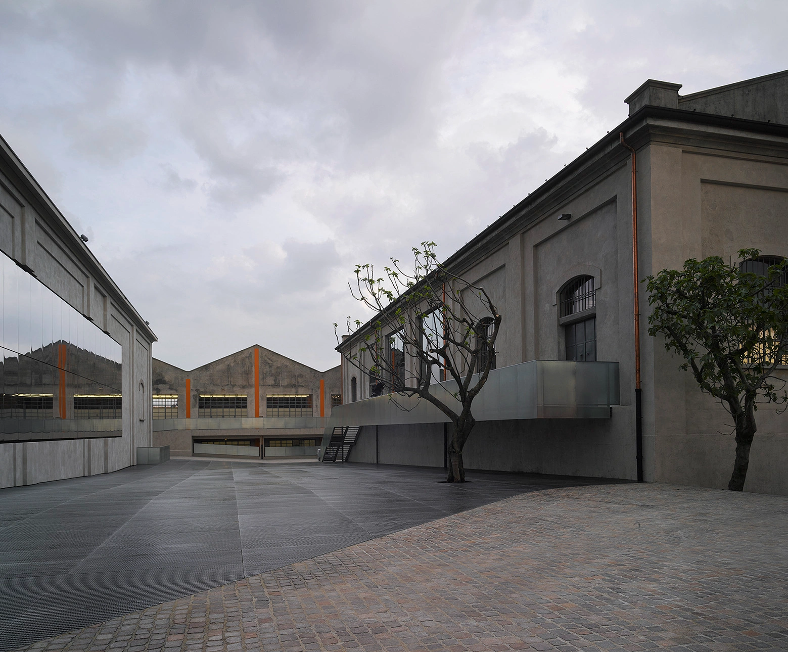 Fondazione Prada by OMA — The courtyard at Fondazione Prada reveals the project's deliberate spatial fragmentation through a composition of contrasting architectural volumes.