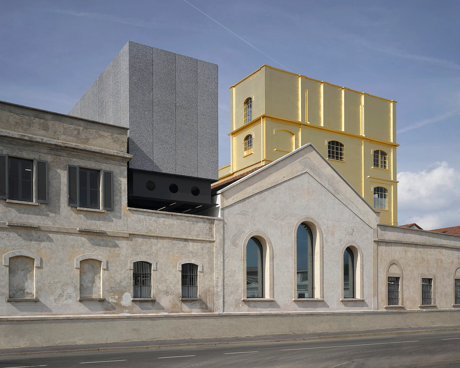 Fondazione Prada by OMA — The Fondazione Prada courtyard presents a deliberate collision of architectural languages across three distinct structures.