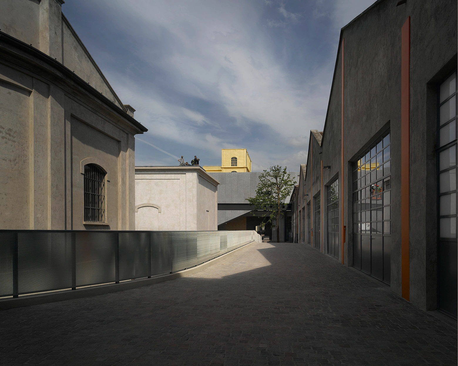 Fondazione Prada by OMA — A paved courtyard frames the architectural heterogeneity of Fondazione Prada's adaptive reuse complex.