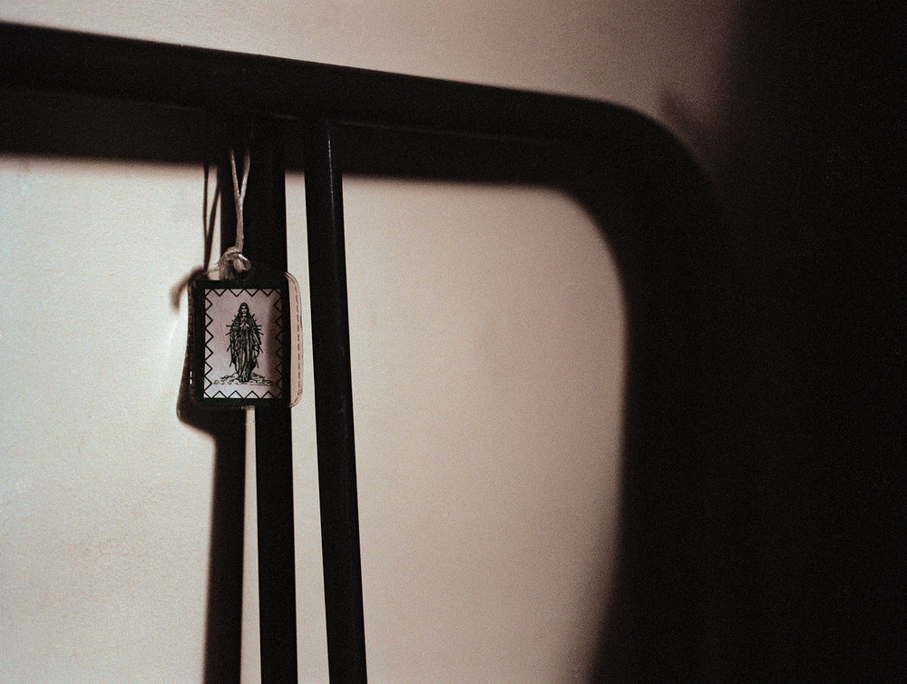 After Magdalene by Ethna Rose O'Regan — A small devotional scapular hangs from black cord against the institutional wall of the disused Magdalene Laundry.