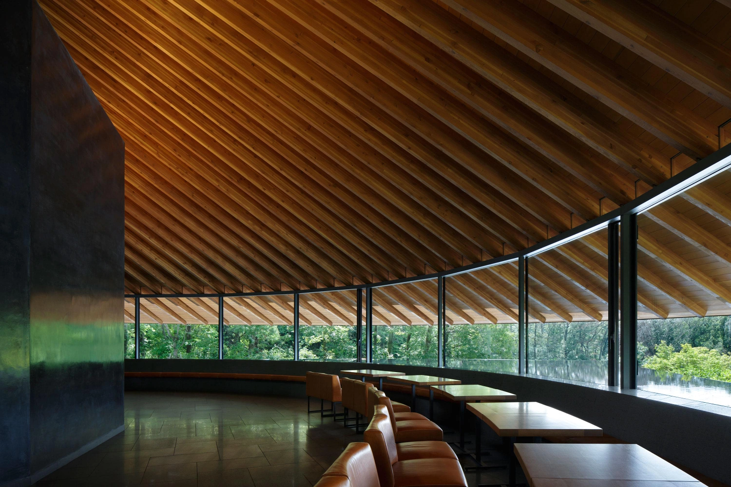 Sayama Lakeside Cemetery Community Hall by Hiroshi Nakamura & NAP — The timber-lined interior of the Sayama Lakeside Cemetery Community Hall frames the forest at eye level through continuous glazing.