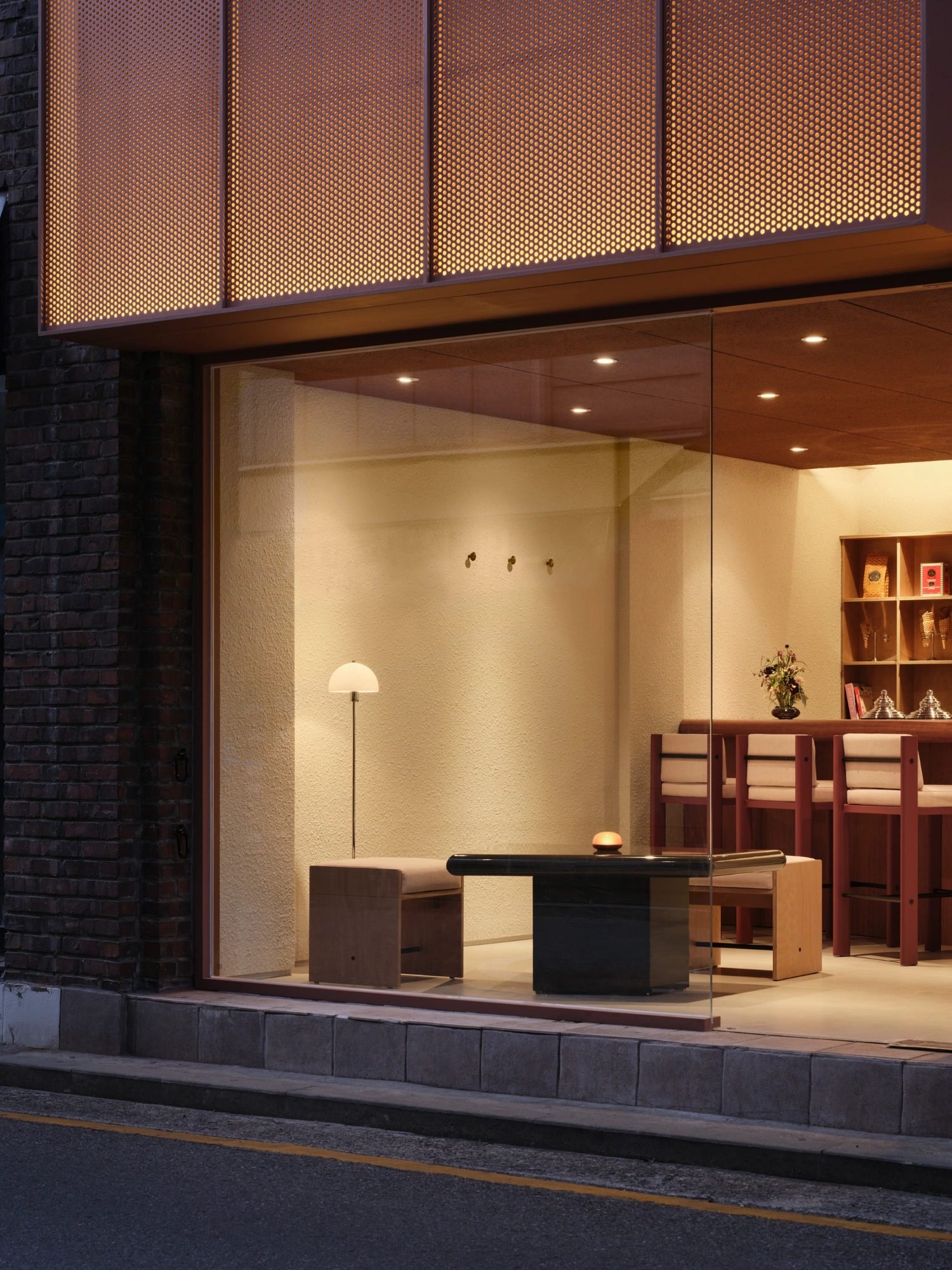 PINOCCHIO Gelato + Coffee Shop by WARP AND WOOF — A gelato and coffee shop storefront at dusk reveals its interior through expansive frameless glazing.