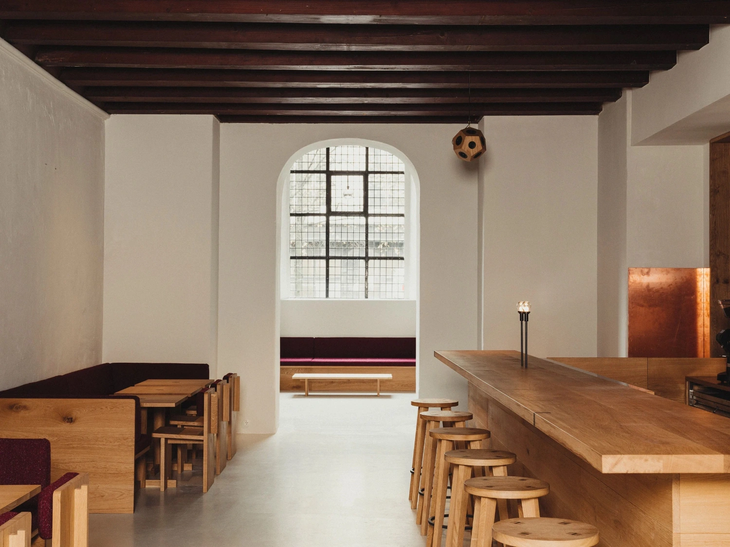 Nikolaj Kunsthal Café + Boutique by Engel Architects by MEE Studio — The café interior presents a linear sequence of wooden furniture and fixtures aligned along the counter and benches.