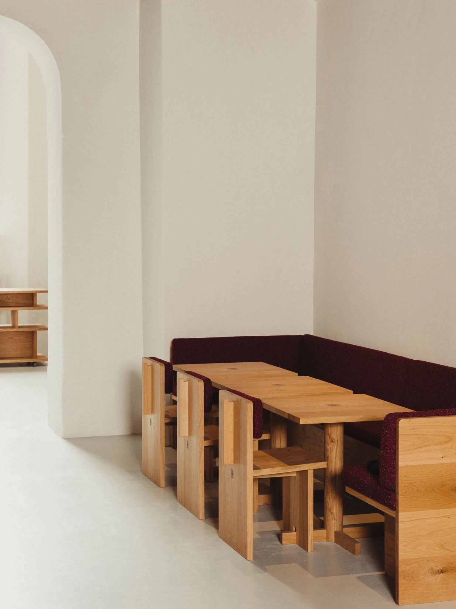 Nikolaj Kunsthal Café + Boutique by Engel Architects by MEE Studio — Nikolaj Kunsthal's café seating arrangement features a linear composition of stacked wooden stools with turned legs positioned beneath a timber counter.