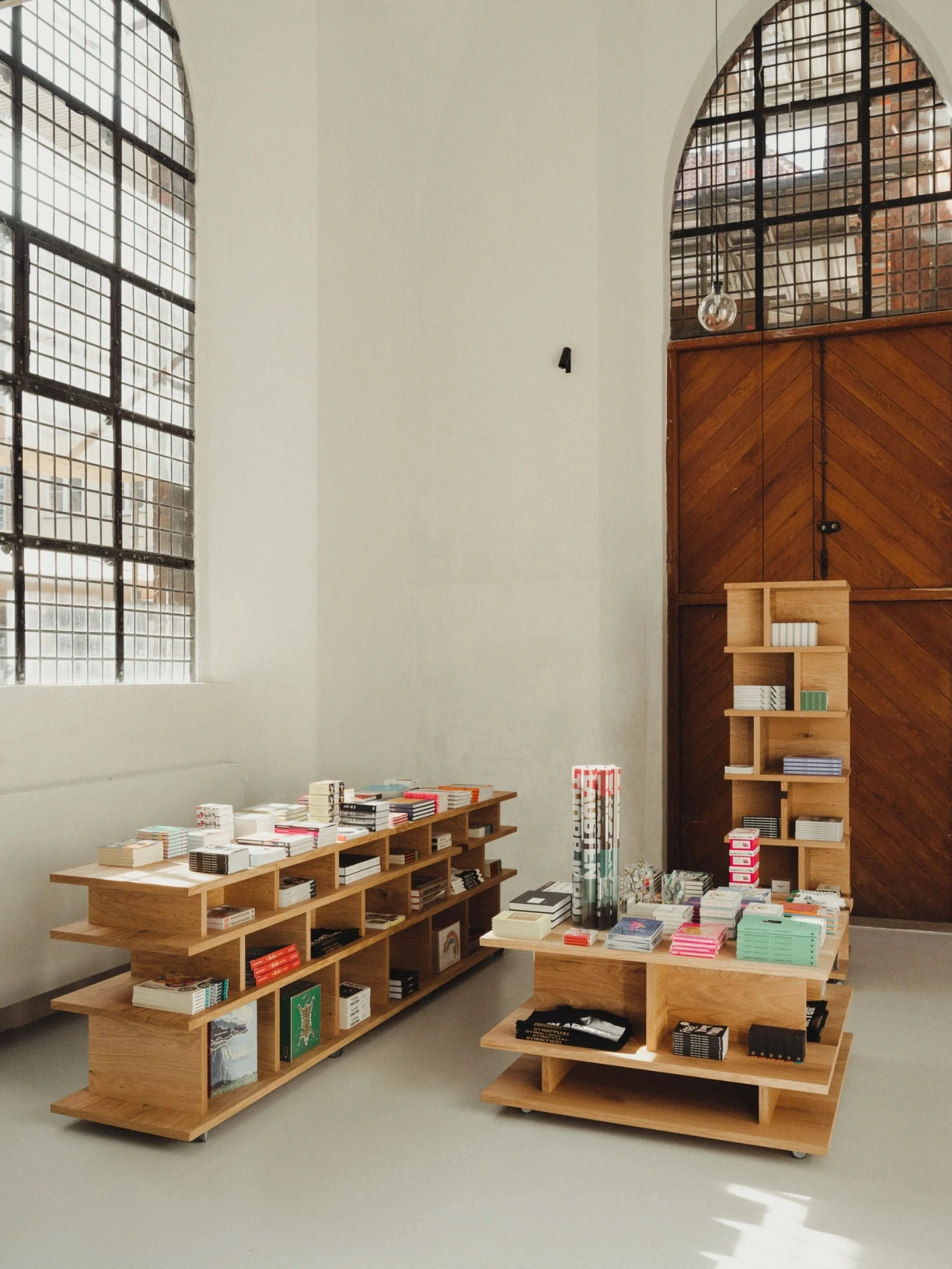 Nikolaj Kunsthal Café + Boutique by Engel Architects by MEE Studio — Wooden display and storage furniture organized across a light-filled interior space.