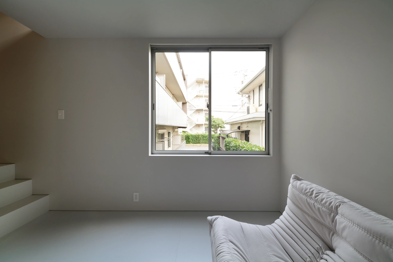 Retreat House by Arii Irie Architects — A spare bedroom on the upper floor frames the neighboring residential context through a horizontal sliding window.