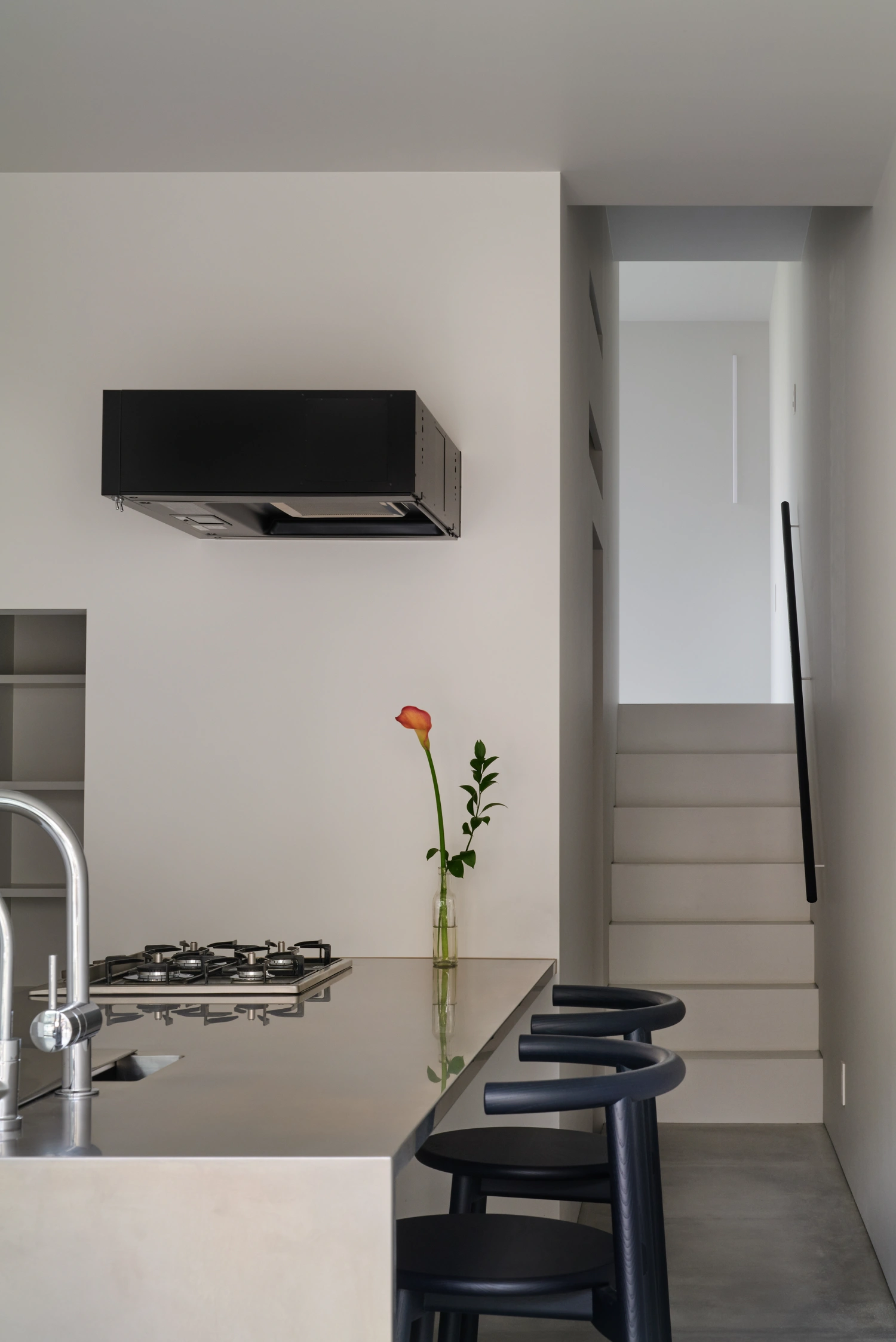 Retreat House by Arii Irie Architects — The kitchen interior reveals a compressed spatial strategy where white render walls frame a minimal cooking zone.