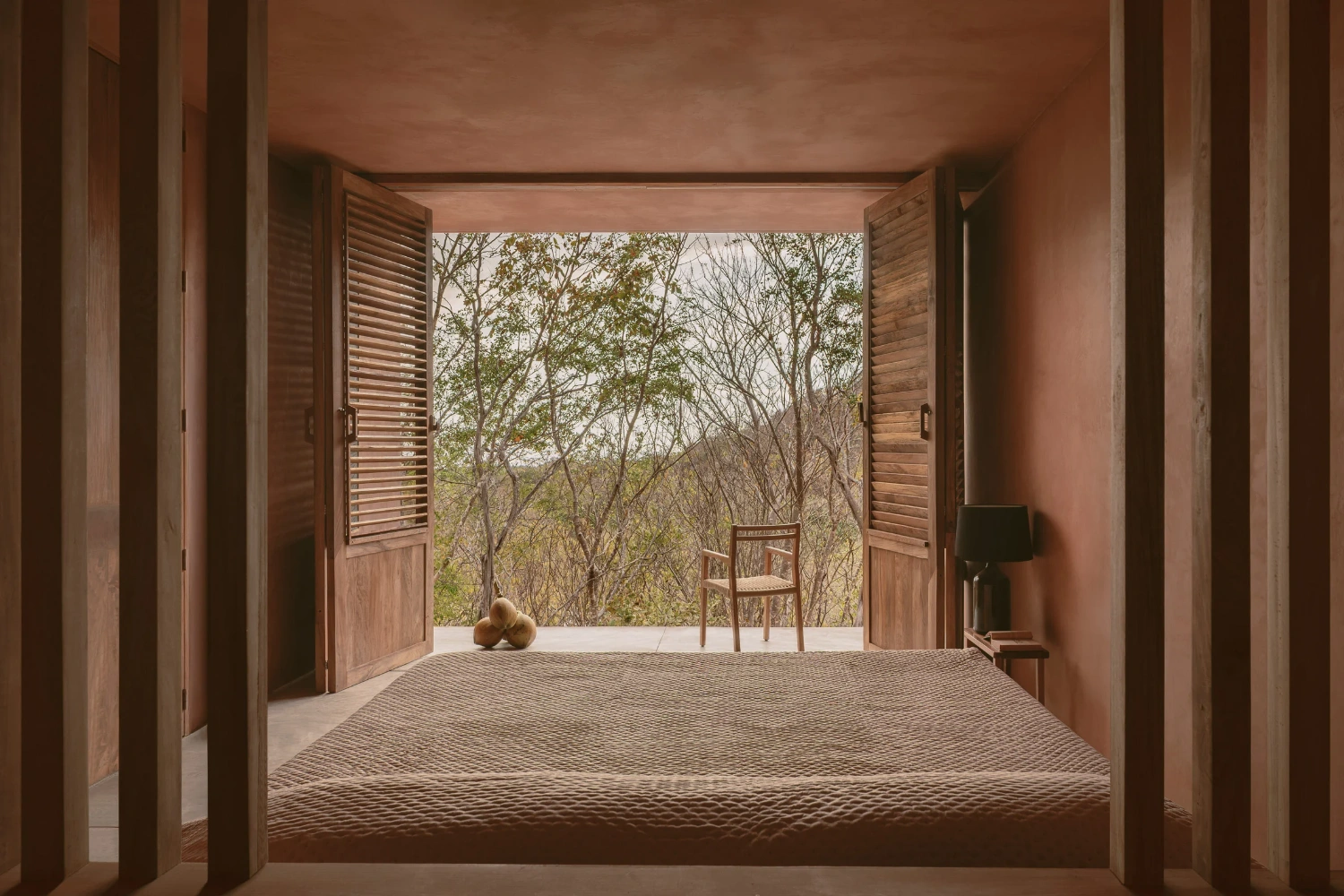 Casa Tobi by Espacio 18 Arquitectura — A bed frame occupies the foreground of an open-air bedroom pavilion, its woven textile surface catching raking light.