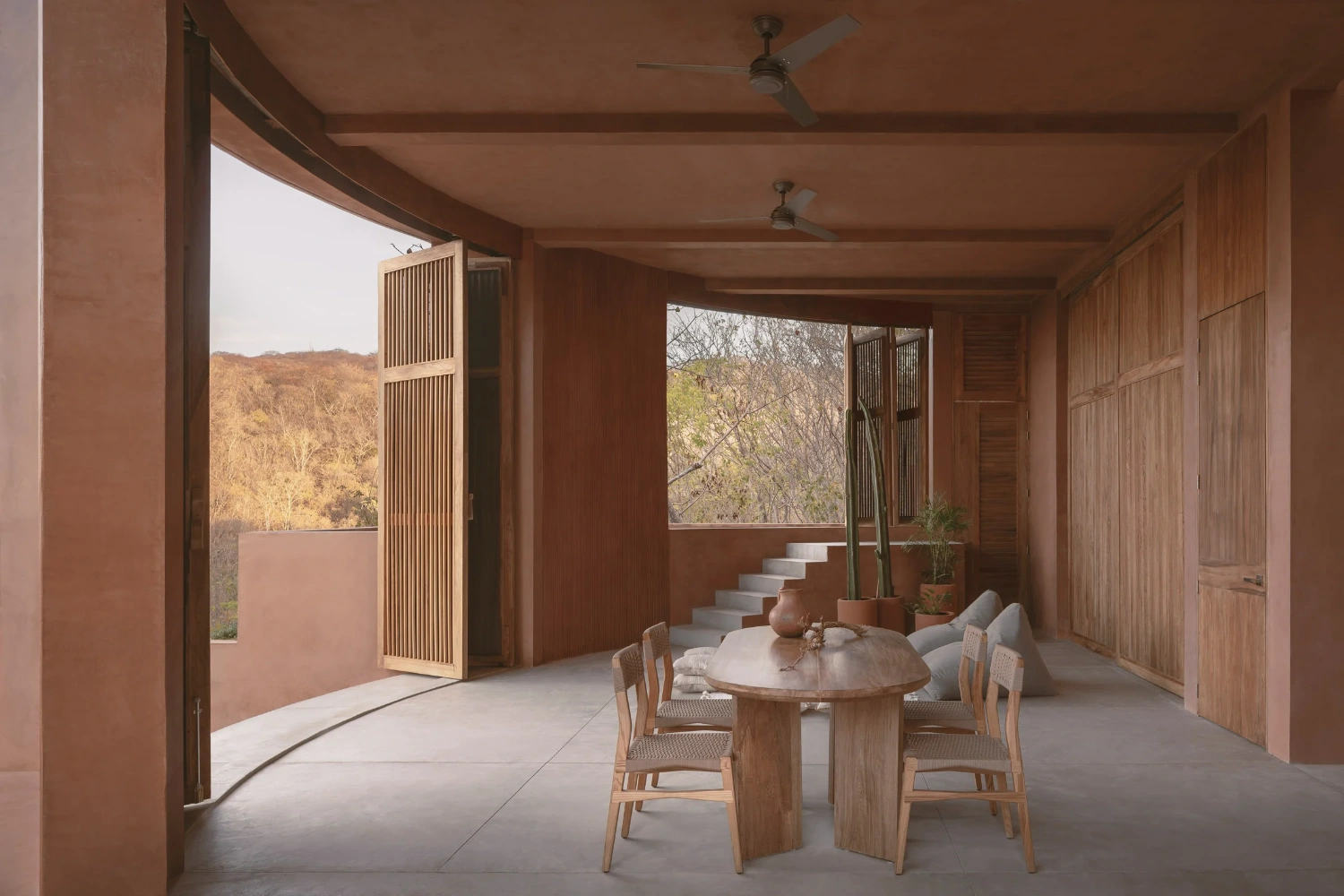 Casa Tobi by Espacio 18 Arquitectura — A covered loggia extends into the landscape, its terracotta render walls framing views toward dry hillside.