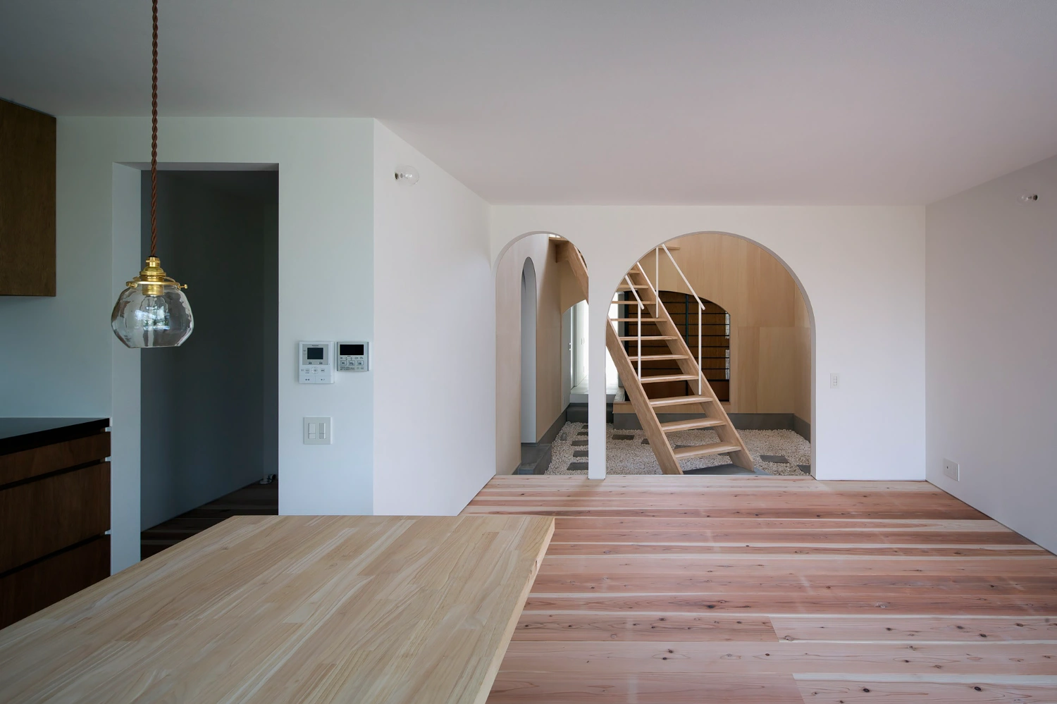 Courtyard in Kudamatsu by Container Design — A double-height interior volume reveals the project's spatial strategy through a barrel-vaulted plywood ceiling and paired arched openings that frame views...