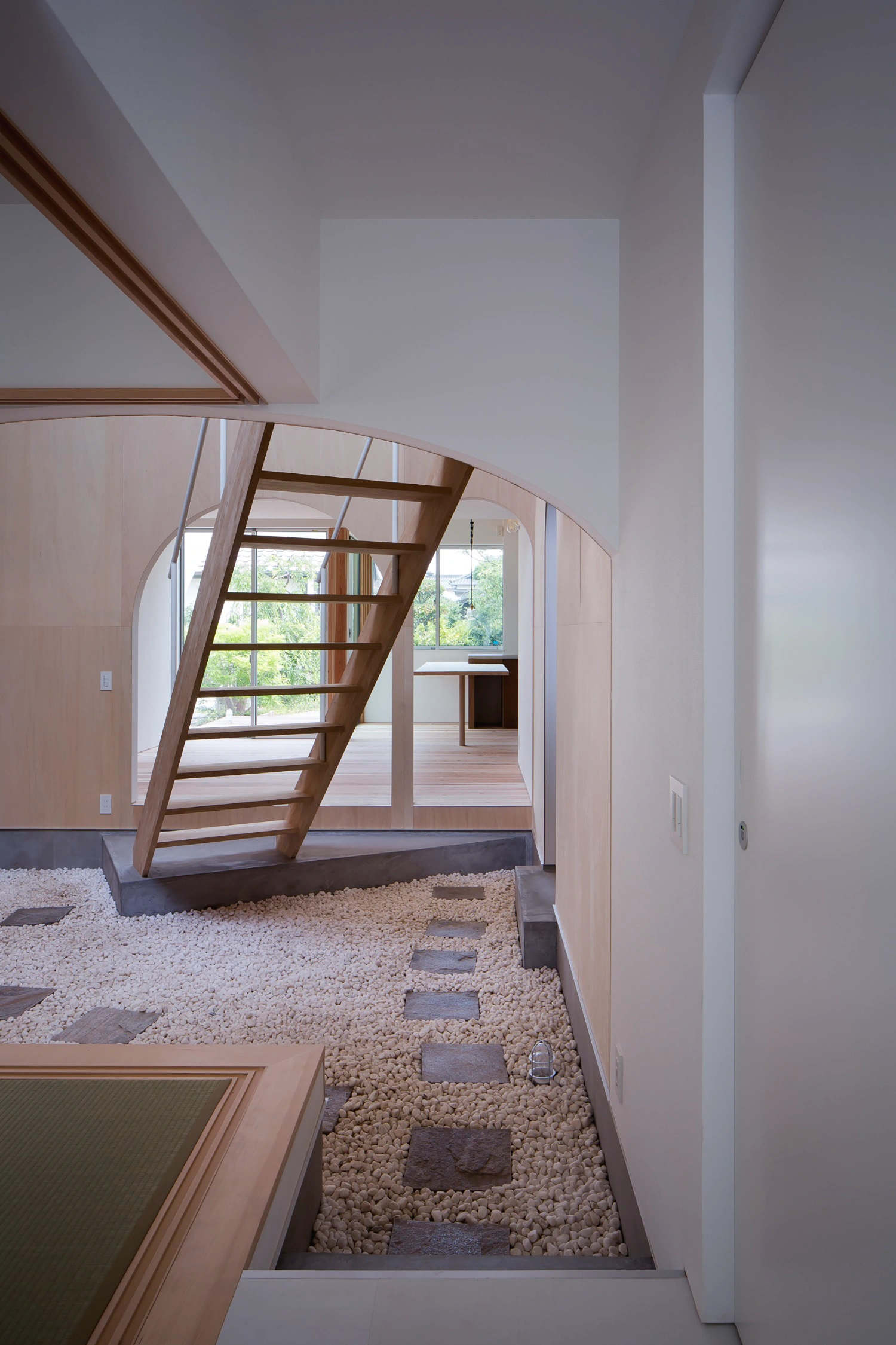 Courtyard in Kudamatsu by Container Design — A passage space defined by a barrel-vaulted plywood ceiling that spans the full width, creating a warm, unified envelope.