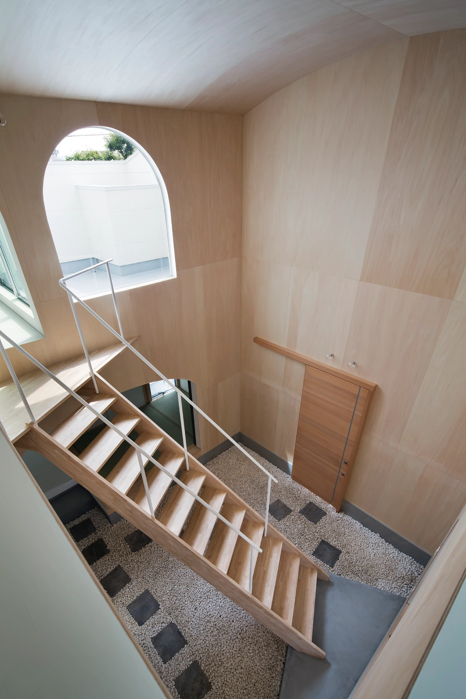 Courtyard in Kudamatsu by Container Design — Overhead view of the diagonal timber staircase within the Courtyard's central volume, revealing the structural logic of the passage.