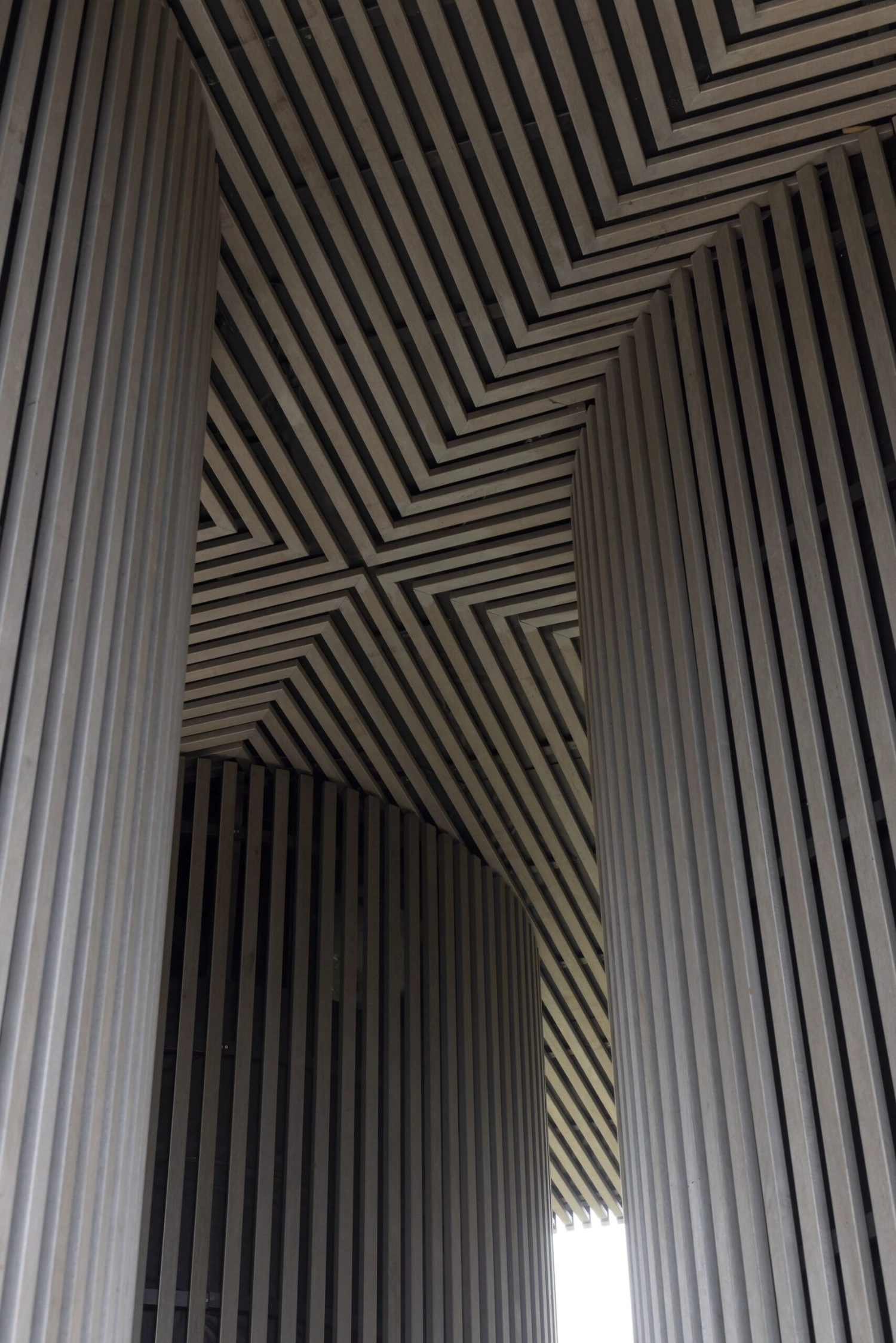 Dolmen by Space Encounters — An interior view looking upward through the structure reveals the geometric complexity of the corrugated metal ceiling system.