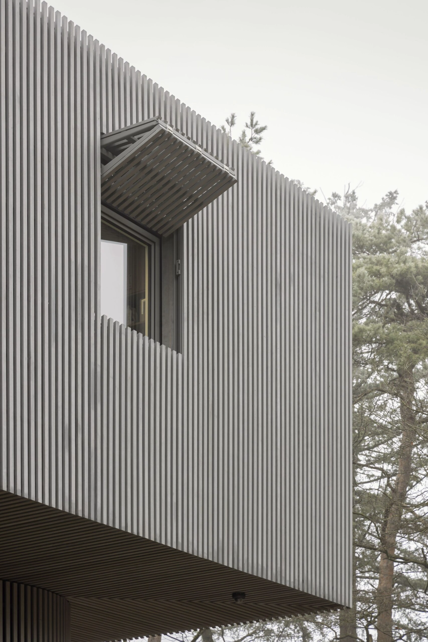 Dolmen by Space Encounters — A frontal elevation of the elevated chamber reveals the structure's primary facade composed of continuous vertical corrugated metal cladding in grey,...