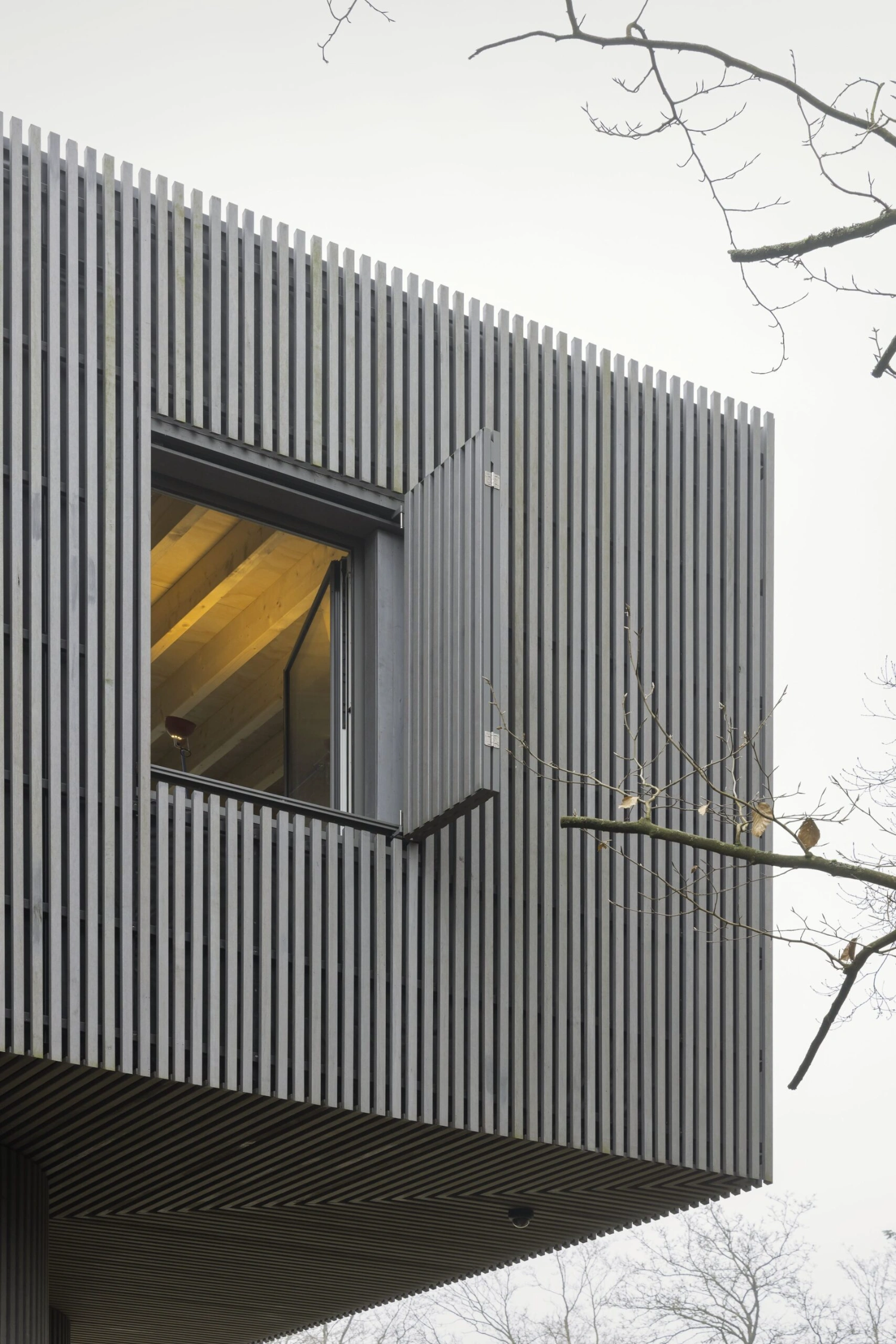 Dolmen by Space Encounters — This elevation captures the structure's primary facade with vertical corrugated metal cladding in charcoal grey, its uniform ribbed texture creating a...