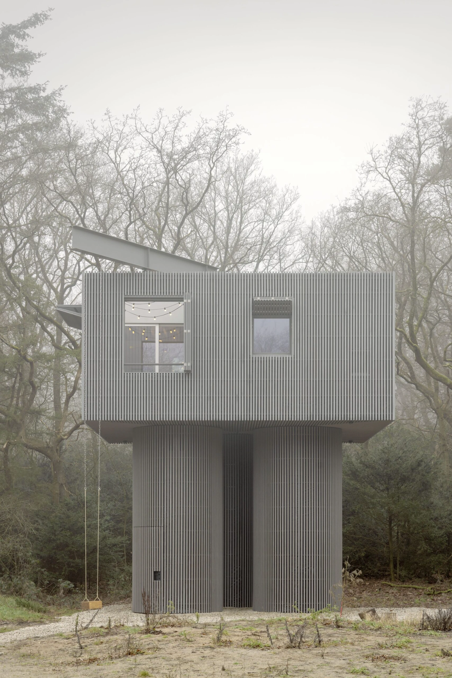 Dolmen by Space Encounters — A corrugated metal tower rises from a forest clearing, its vertical ribbed steel cladding uniform and continuous across the facade.