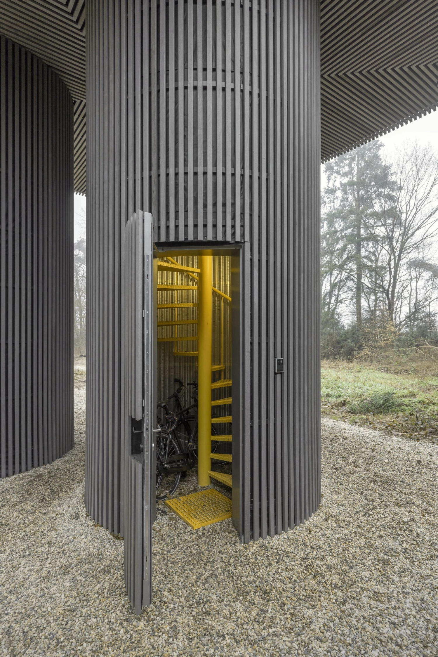 Dolmen by Space Encounters — A cylindrical structure wrapped in continuous vertical corrugated metal cladding dominates the composition.